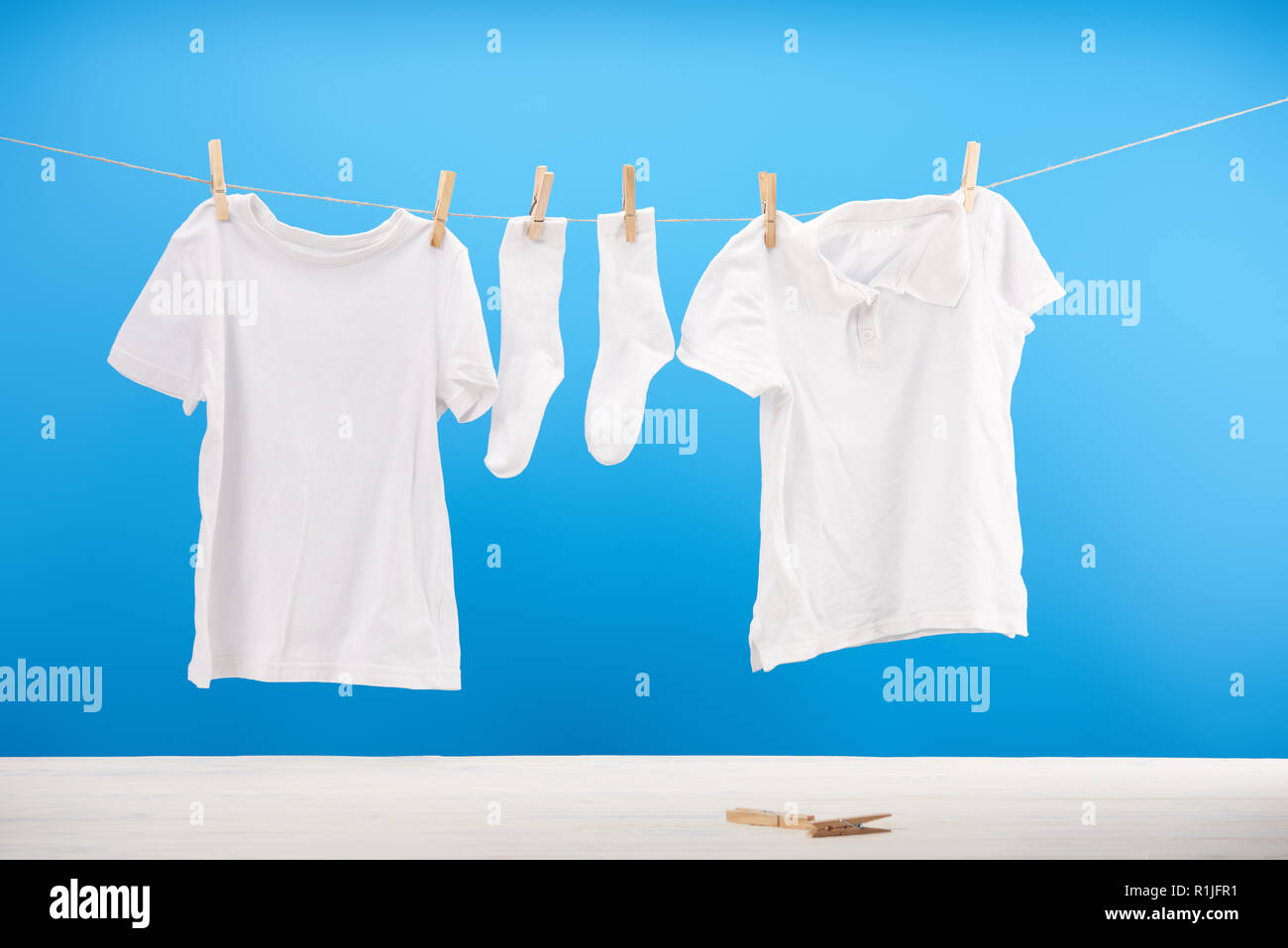 clean white socks and t-shirts hanging on clothesline on blue Stock Photo