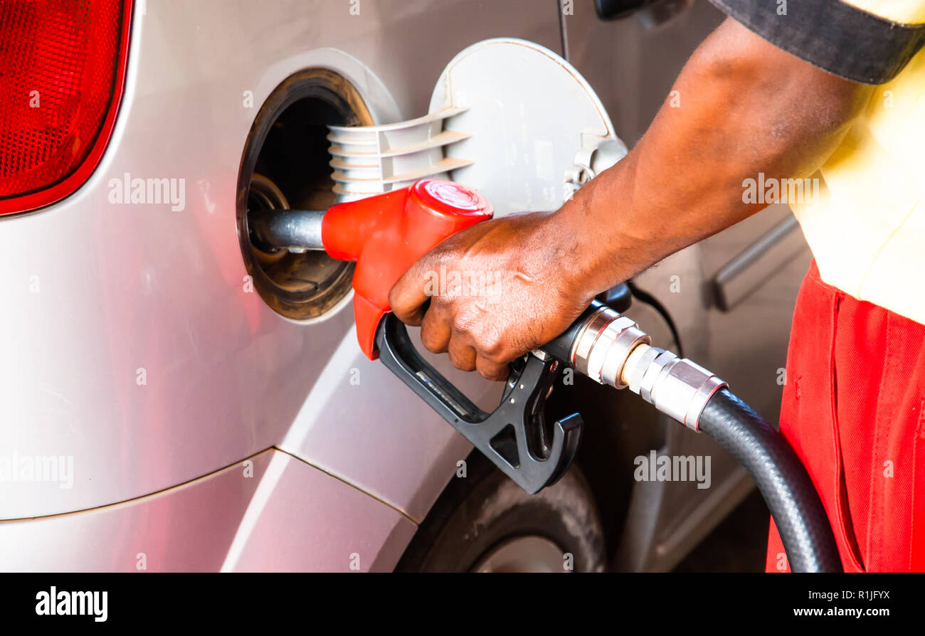 Hand of worker man refuelling a car at the petrol station. Concept photo for use of fossil fuels (gasoline, diesel) in combustion engines, air polluti Stock Photo