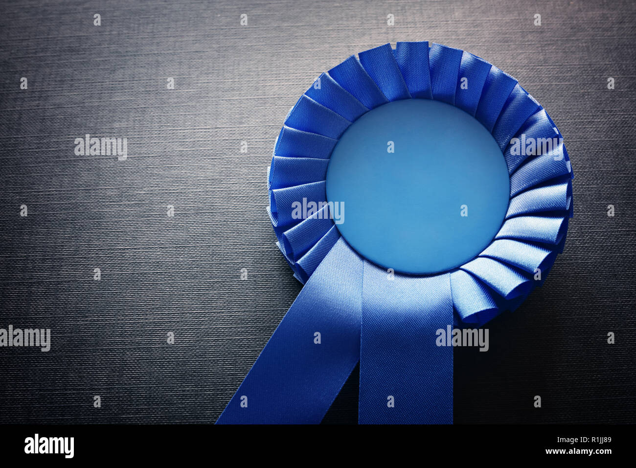 Blue award rosette with ribbons and copy space on black background Stock Photo