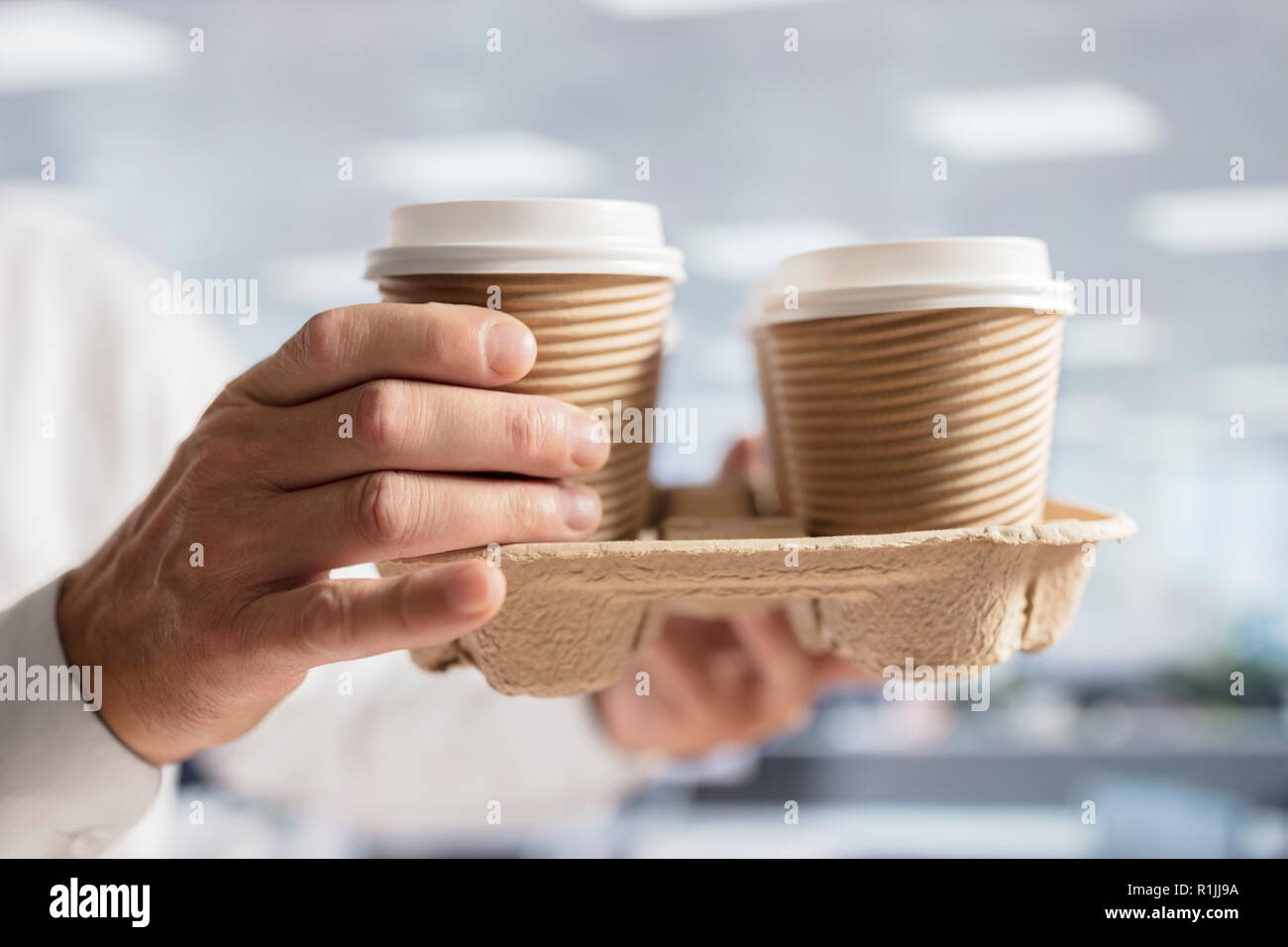 Businessman carrying coffee take out disposable cups for office meeting Stock Photo