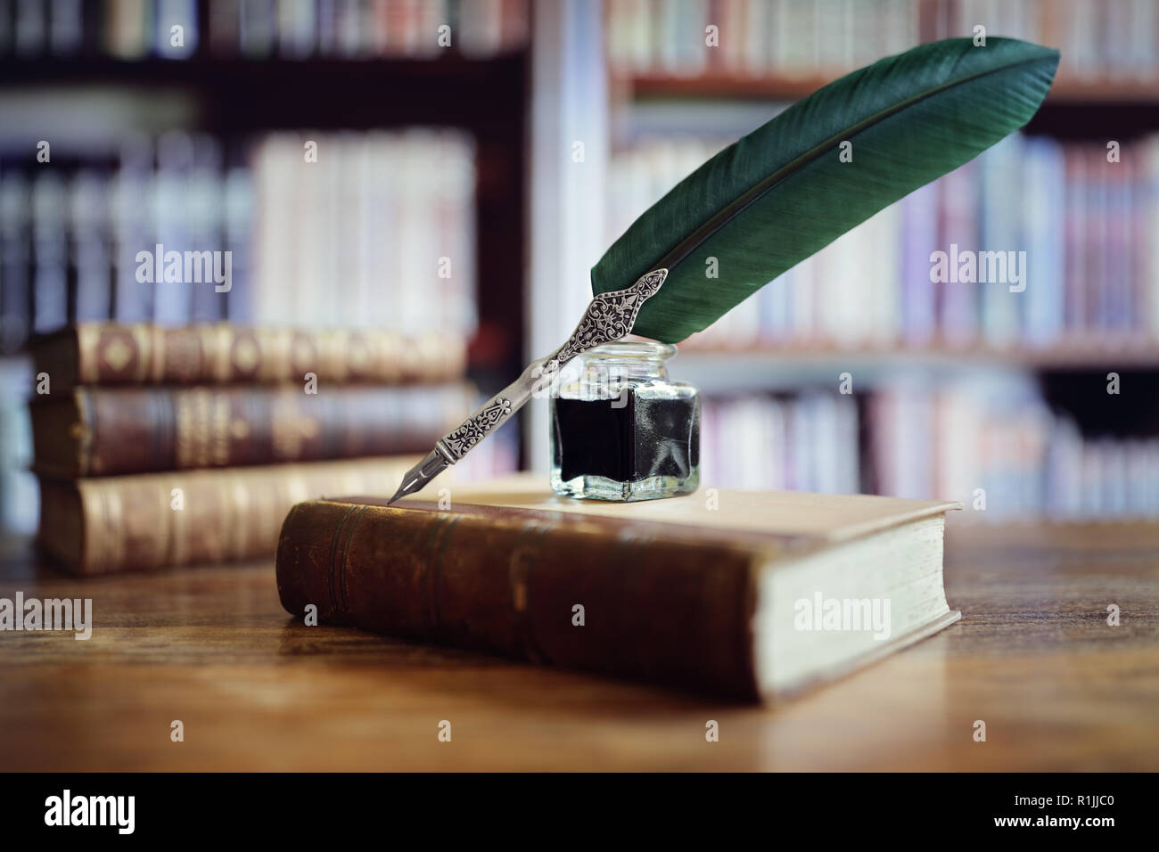 Quill pen and ink well resting on an old book in a library concept for literature, writing, author and history Stock Photo