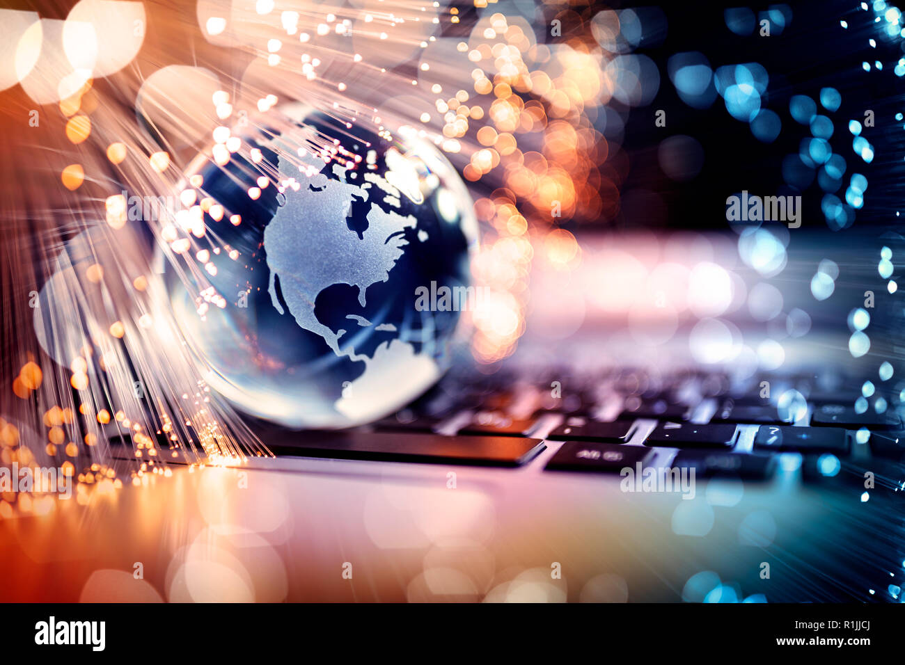 Fibre optics around blue planet on laptop computer keyboard Stock Photo