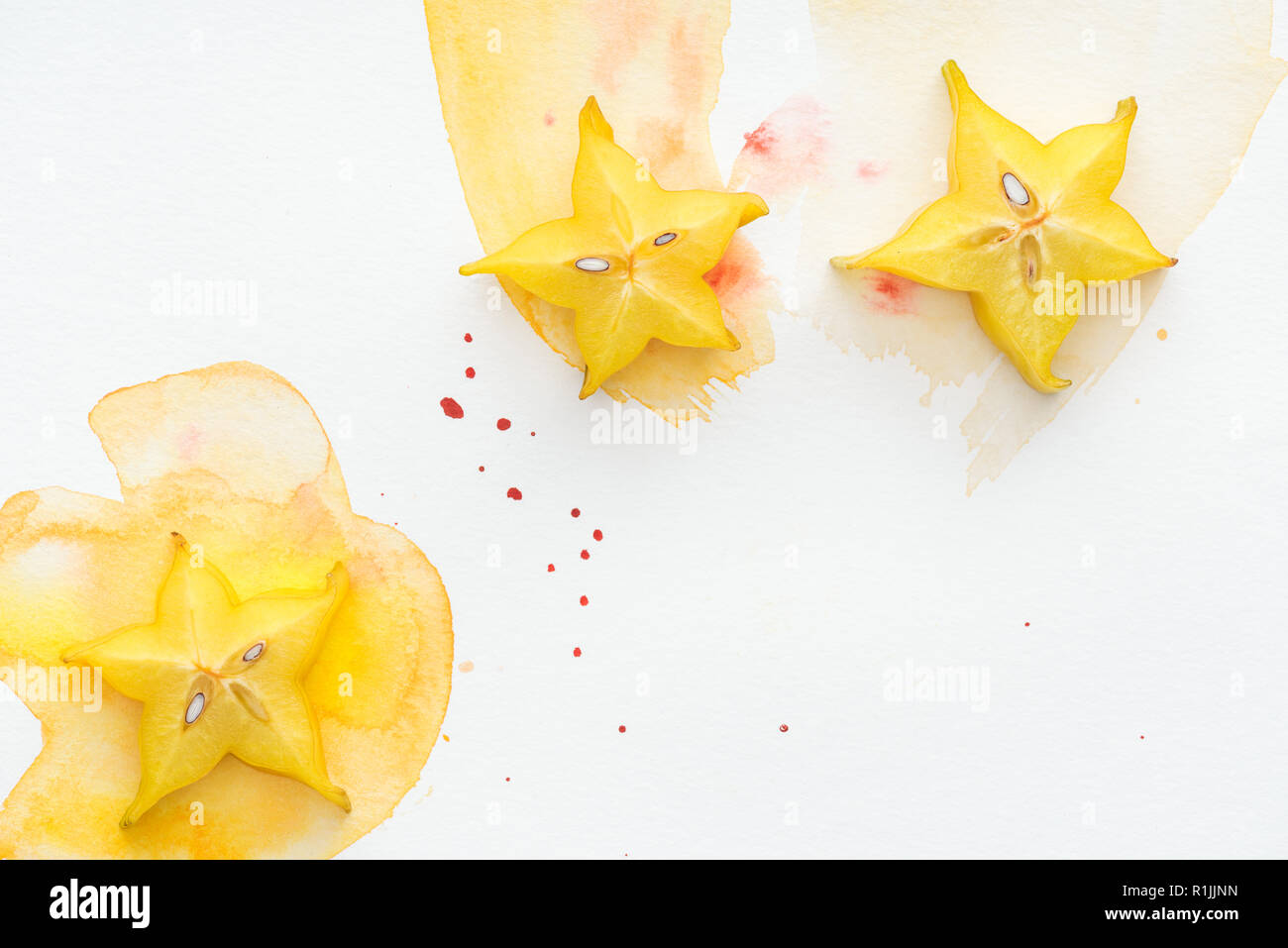 top view of three carambolas on white surface with yellow watercolor Stock Photo