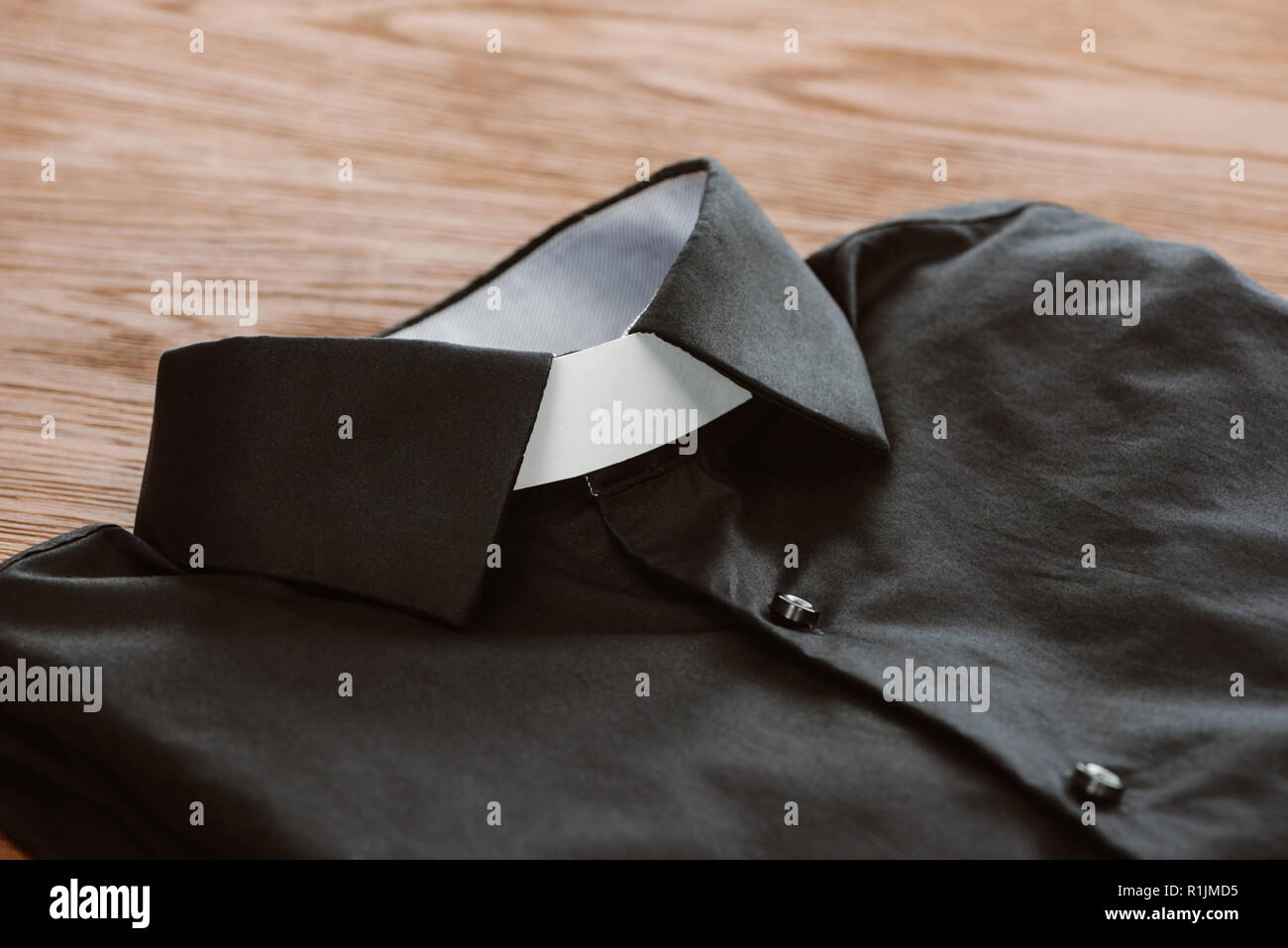 close-up shot of clerical shirt with white collar on wooden surface Stock Photo