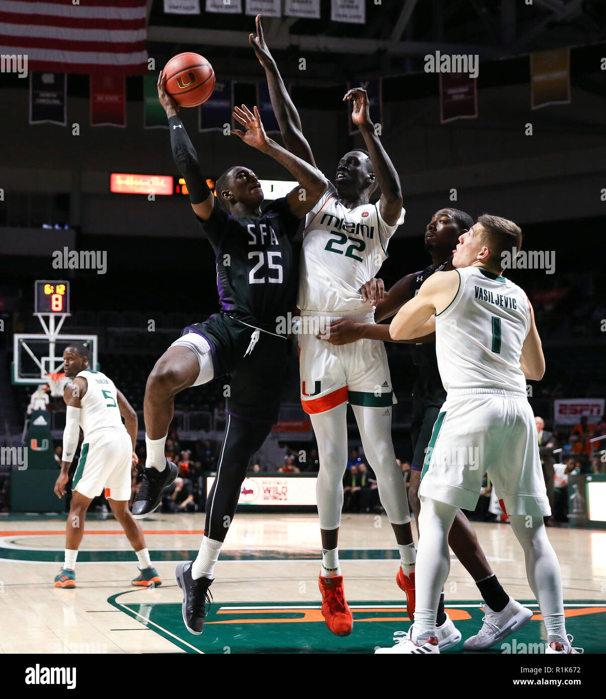 Coral Gables, Florida, USA. 13th Nov, 2018. Stephen F. Austin Lumberjacks forward Karl Nicholas (25) shoots to the basket, challenged by Miami Hurricanes forward Deng Gak (22), as Stephen F. Austin Lumberjacks forward Mitchell Seraille (3) (hidden) and Miami Hurricanes guard Dejan Vasiljevic (1) follow the action, during the second half of the NCAA mens basketball game between the Stephen F. Austin Lumberjacks and the University of Miami Hurricanes at the Watsco Center in Coral Gables, Florida. The Hurricanes won 96 - 58. Mario Houben/CSM/Alamy Live News Stock Photo
