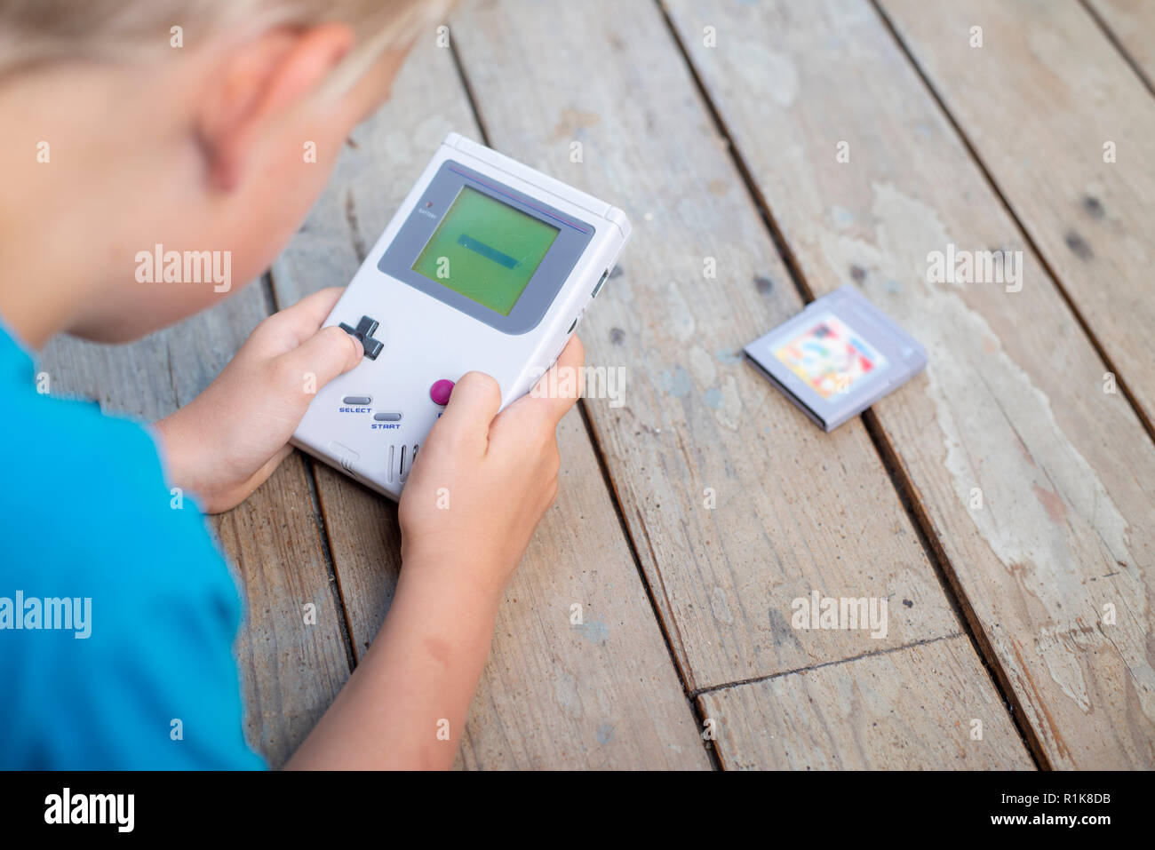 Young boy using his nintendo gameboy to play computer games. Nineties setting. indoors setting. Stock Photo