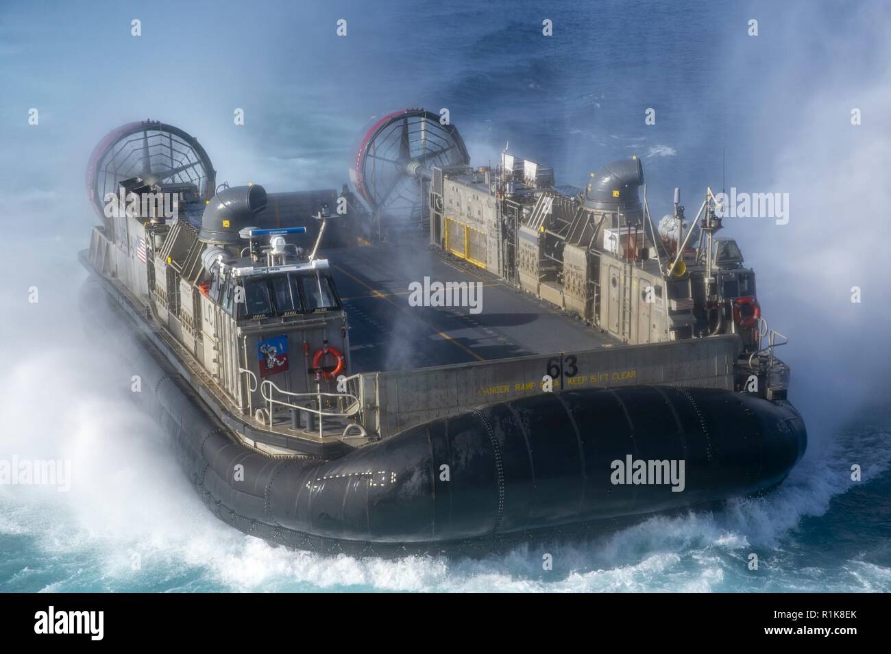 PACIFIC OCEAN (Oct. 10, 2018) Landing craft air cushion (LCAC) 63, assigned to Assault Craft Unit (ACU) 5, approaches the well deck of the amphibious assault ship USS Bonhomme Richard (LHD 6). Bonhomme Richard is operating in the U.S. 3rd Fleet area of operations. Stock Photo