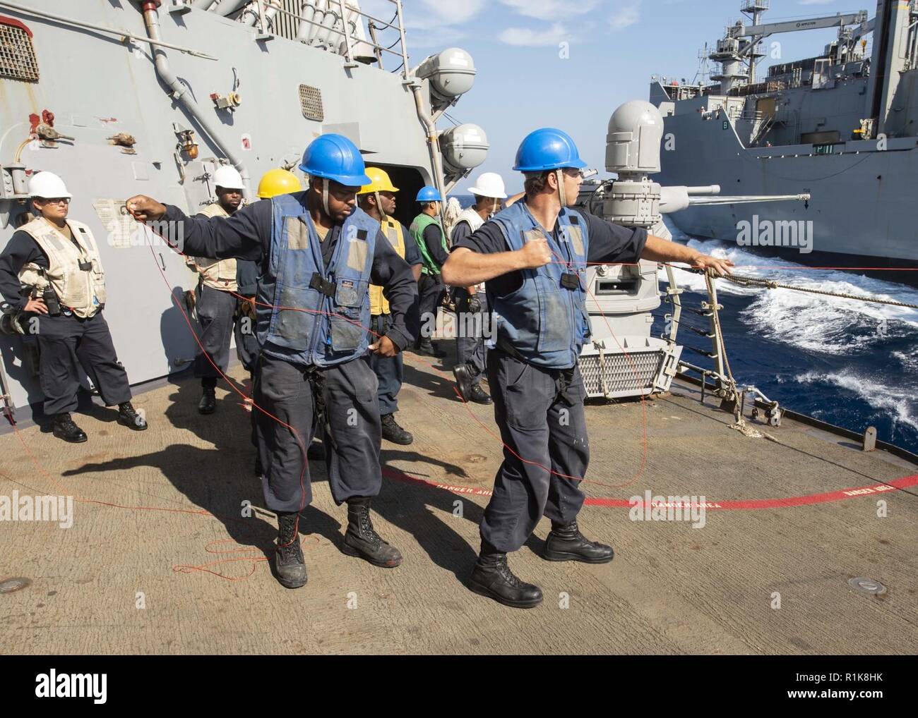 MEDITERRANEAN SEA (Oct. 6, 2018) Sailors heave a shot line aboard the Arleigh Burke-class guided-missile destroyer USS Arleigh Burke (DDG 51) during a replenishment-at-sea with the dry cargo and ammunition ship USNS Medgar Evers (T-AKE 13) in the Mediterranean Sea Oct. 6, 2018. Arleigh Burke, homeported at Naval Station Norfolk, is conducting naval operations in the U.S. 6th Fleet area of operations in support of U.S. national security interests in Europe and Africa. Stock Photo