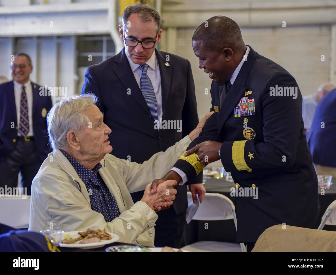 ALAMEDA, Calif.  (Oct. 8 2018) Rear Adm. Cedric Pringle, right, commander of Expeditionary Strike Group (ESG) 3, greets retired Chief Petty Officer, Richard 'Johnny' Johnson, a Pearl Harbor survivor, during a luncheon hosted aboard the USS Hornet Museum by the Naval Order of the United States during San Francisco Fleet Week 2018. San Francisco Fleet Week is an opportunity for the American public to meet their Navy, Marine Corps and Coast Guard teams and experience America‚Äôs sea services. During Fleet Week, service members participate in various community service events, showcase capabilities Stock Photo