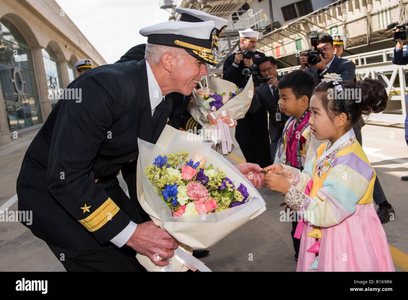 JEJU ISLAND, Republic of Korea, (Oct. 12, 2018) Rear Admiral. Karl Thomas, commander, Battle Force 7th Fleet, Task Force 70, Carrier Strike Group 5, exchanges gifts with a young girl pier side at the Republic of Korea (ROK) Navy Base in Jeju. Thomas commands the USS Ronald Reagan (CVN 76) Carrier Strike Group which is forward deployed to the U.S. 7th Fleet area of operations in support of security and stability in the Into-Pacific region. Stock Photo