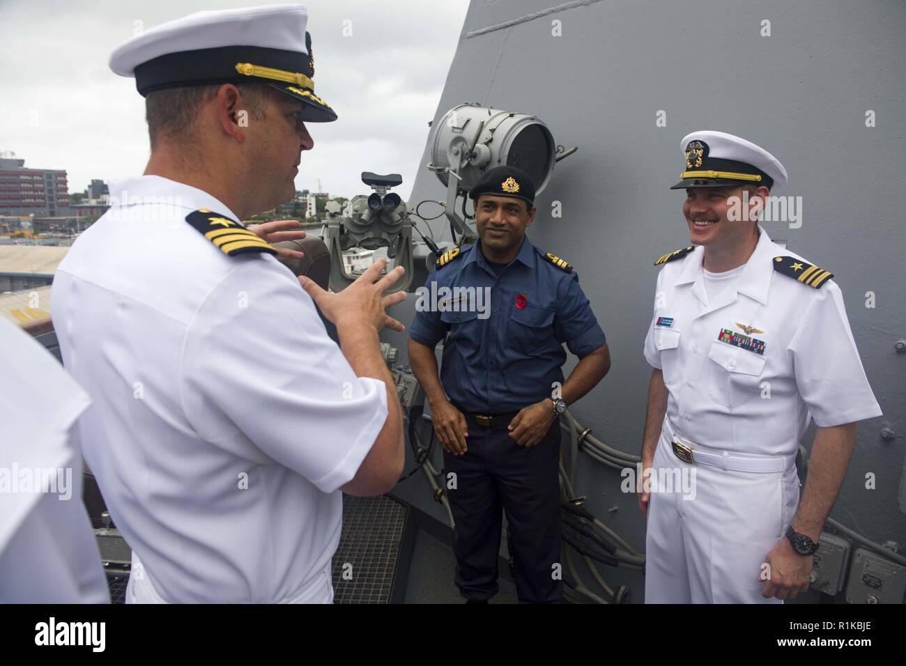 PORT OF SUVA, Fiji (Oct. 14, 2018) Cmdr. Andy Strickland, commanding officer of Arleigh Burke-class guided-missile destroyer USS Shoup (DDG 86), talks with Cmdr. Ledua Yaco, Republic of Fiji Military Forces, and Lt. Cmdr. William Hinson, on the bridgewing as the ship pulls into the Port of Suva, Fiji Oct. 14, 2018. Shoup is currently participating in the Oceania Maritime Security Initiative (OMSI) program, a Secretary of Defense program leveraging Department of Defense assets transiting the region to increase the Coast Guard’s maritime domain awareness, ultimately supporting its maritime law e Stock Photo