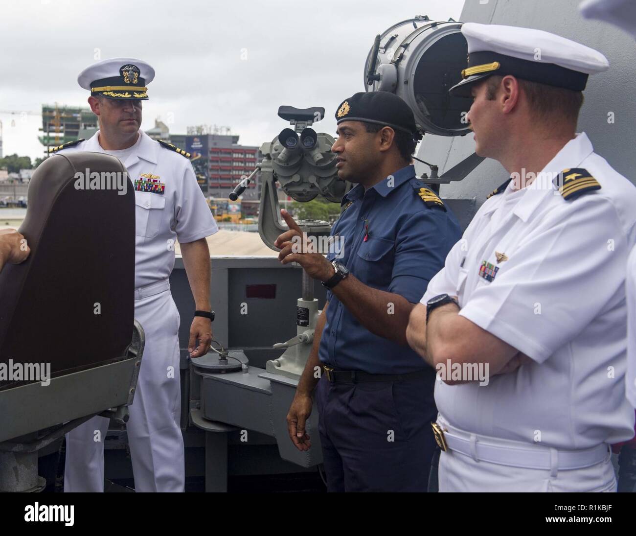 PORT OF SUVA, Fiji (Oct. 14, 2018) Cmdr. Andy Strickland, commanding officer of Arleigh Burke-class guided-missile destroyer USS Shoup (DDG 86), listens to Cmdr. Ledua Yaco, Republic of Fiji Military Forces, and Lt. Cmdr. William Hinson, on the bridgewing as the ship pulls into the Port of Suva, Fiji Oct. 14, 2018. Shoup is currently participating in the Oceania Maritime Security Initiative (OMSI) program, a Secretary of Defense program leveraging Department of Defense assets transiting the region to increase the Coast Guard’s maritime domain awareness, ultimately supporting its maritime law e Stock Photo