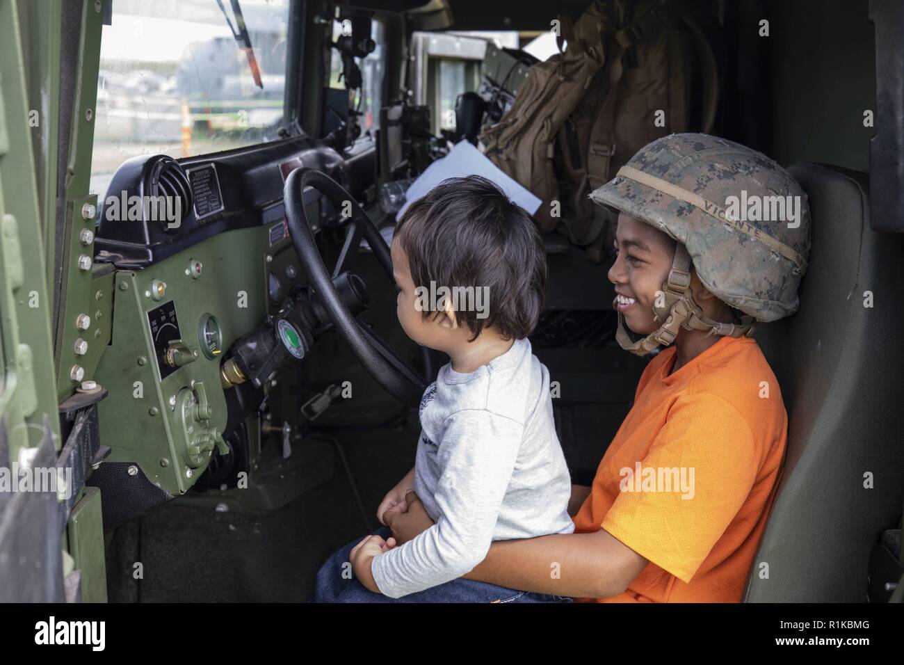 Children sit in the driver’s seat of a High Mobility Multipurpose Wheeled Vehicle assigned to Combat Logistics Battalion 3 during the Waimea Fall Festival at the Waimea District Park, Oct. 13, 2018. U.S. Marines with Marine Medium Tiltrotor Squadron (VMM) 363, nicknamed the Lucky Red Lions, flew one of their aircraft from Marine Corps Base Hawaii on Oahu to the Waimea Fall Festival, providing a static display and subject matter experts for a first-hand experience to the festival’s attendants. The squadron arrived to Hawaii earlier this year increasing the combat capability and crisis response  Stock Photo