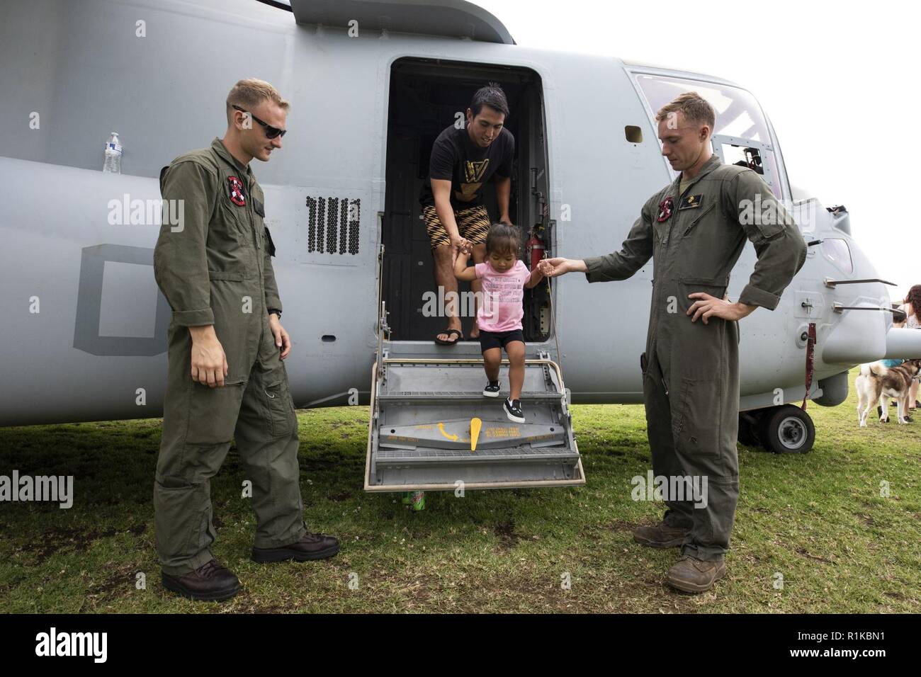 U.S. Marines with Marine Medium Tiltrotor Squadron (VMM) 363, nicknamed the Lucky Red Lions, assist a child exiting a MV-22B Osprey aircraft during the Waimea Fall Festival at the Waimea District Park, Oct. 13, 2018. VMM-363 flew one of their aircraft from Marine Corps Base Hawaii on Oahu to the Waimea Fall Festival, providing a static display and subject matter experts for a first-hand experience to the festival’s attendants. The squadron arrived to Hawaii earlier this year increasing the combat capability and crisis response within the Indo-Pacific region. Stock Photo