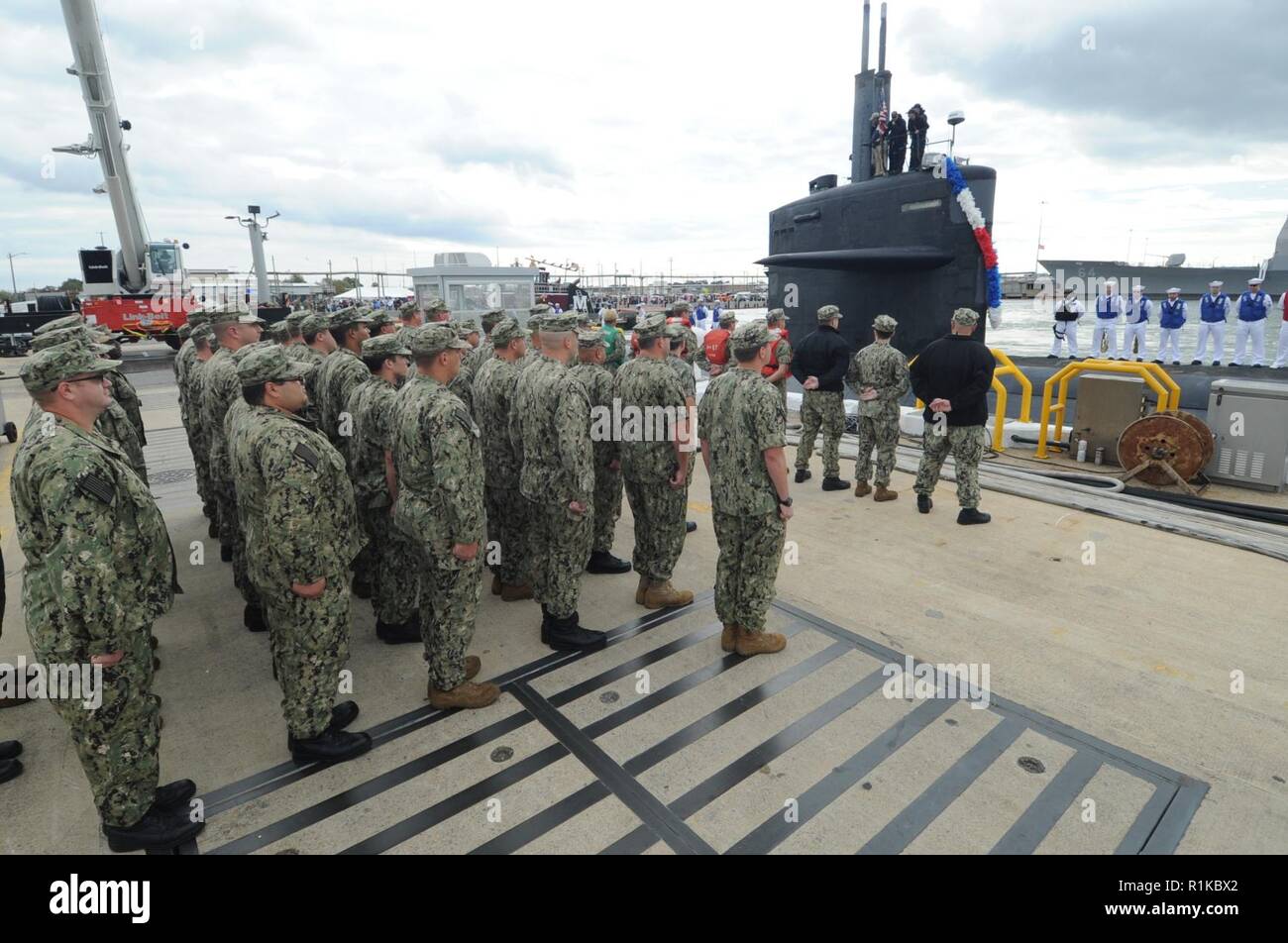 Sailors assigned to Submarine Squadron Six stand pier-side welcoming ...