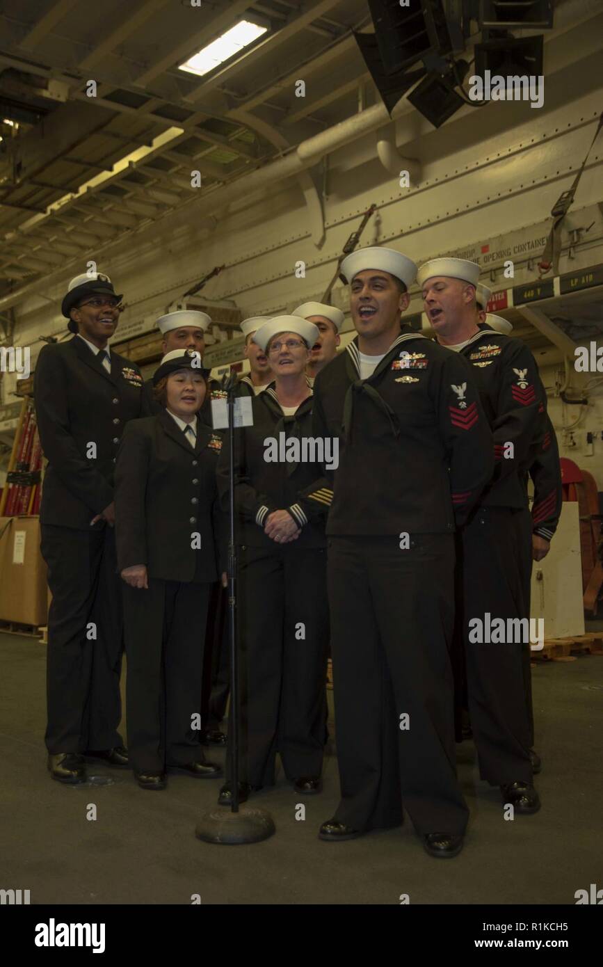 PACIFIC OCEAN (Oct. 10, 2018) Sailors, assigned to the amphibious assault ship USS Bonhomme Richard (LHD 6), sing Anchors Aweigh during the 243rd Navy birthday celebration ceremony held in the ship’s hangar bay. Bonhomme Richard is operating in the U.S. 3rd Fleet area of operations. Stock Photo