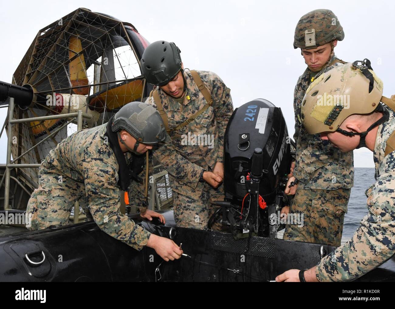 EAST CHINA SEA (Oct. 14, 2018) Cpl. Mateo Johnson, Sgt. Mark Weber, Lance Cpl. Jonah Massey, and Cpl. Nierengarten, assigned to the 31st Marine Expeditionary Unit (MEU), mount an engine to a combat rubber raiding craft aboard a landing craft, air cushion, assigned to Naval Beach Unit 7, during integrated unit level training. The amphibious assault ship USS Wasp (LHD 1), flagship of Wasp Amphibious Ready Group, with embarked 31st Marine Expeditionary Unit, is operating in the Indo-Pacific region to enhance interoperability with partners and serve as a ready-response force for any type of contin Stock Photo
