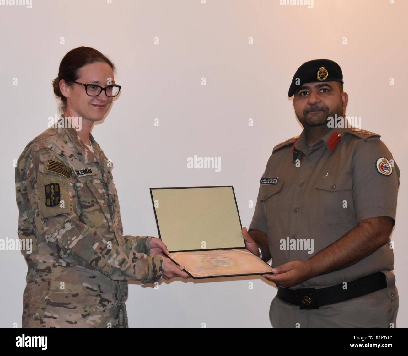 Colonel Dr. Raed R. Altajalli, assistant director of North Medical Military Complex presents Lt. Col. Dawn Coleman, deployed with the 452nd Combat Support Hospital, a token of appreciation for her presentation on surgical care of combat casualties at the North Medical Military Complex, Kuwait on Oct. 4, 2018.      When not deployed, Coleman is an associate professor of surgery and pediatrics as well as the communicable diseases program director at the University of Michigan.     Members of Area Support Group-Kuwait Troop Medical Center and the 452nd Combat Support Hospital increase capabilitie Stock Photo