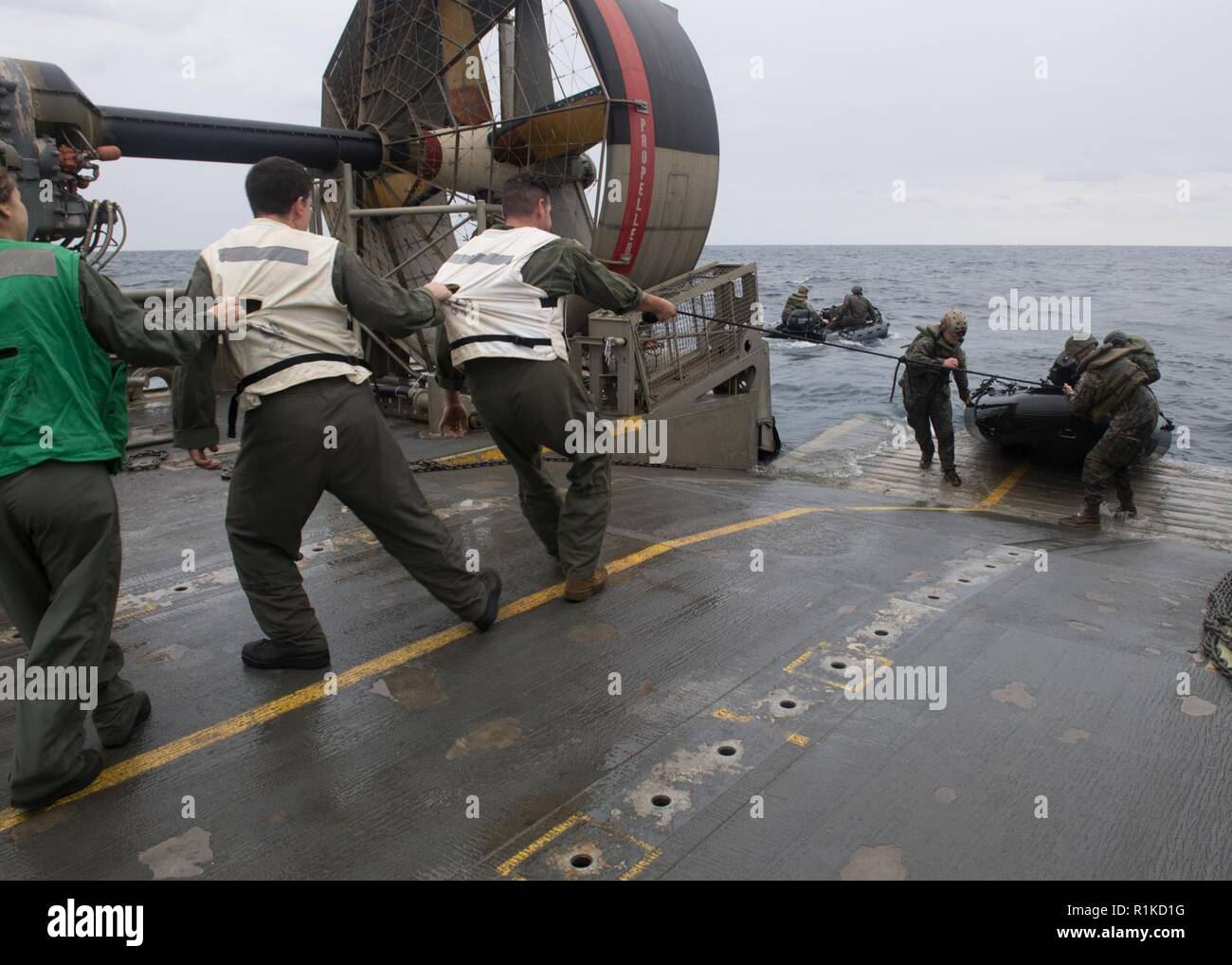 EAST CHINA SEA (Oct. 14, 2018) Sailors, assigned to Naval Beach Unit (NBU) 7,  assist Marines assigned to the 31st Marine Expeditionary Unit (MEU), in pulling in a combat rubber raiding craft from the water aboard a landing craft, air cushion, during integrated unit level training. The amphibious assault ship USS Wasp (LHD 1), flagship of Wasp Amphibious Ready Group, with embarked 31st MEU, is operating in the Indo-Pacific region to enhance interoperability with partners and serve as a ready-response force for any type of contingency. Stock Photo