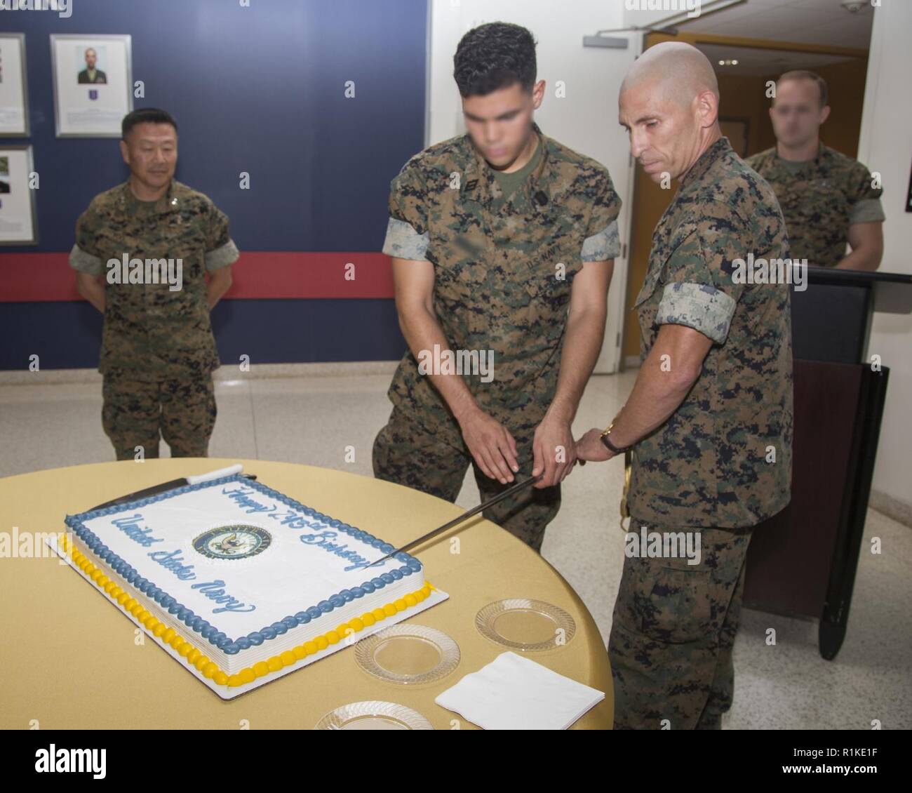 The oldest and youngest Sailors with U.S. Marine Corps Forces, Special Operations Command, cut the ceremonial birthday cake for the Navy’s 243rd birthday at MARSOC Headquarters aboard Marine Corps Base Camp Lejeune, N.C., Oct. 15, 2018.  The oldest Sailor (right) was born in 1968 and the youngest (center) in 1998.  The oldest Sailor passes cake to the youngest Sailor in a tradition that represents the transfer of experience and knowledge.  MARSOC Commander, General Daniel D. Yoo (left), was honored as the guest of honor during the ceremony. Stock Photo