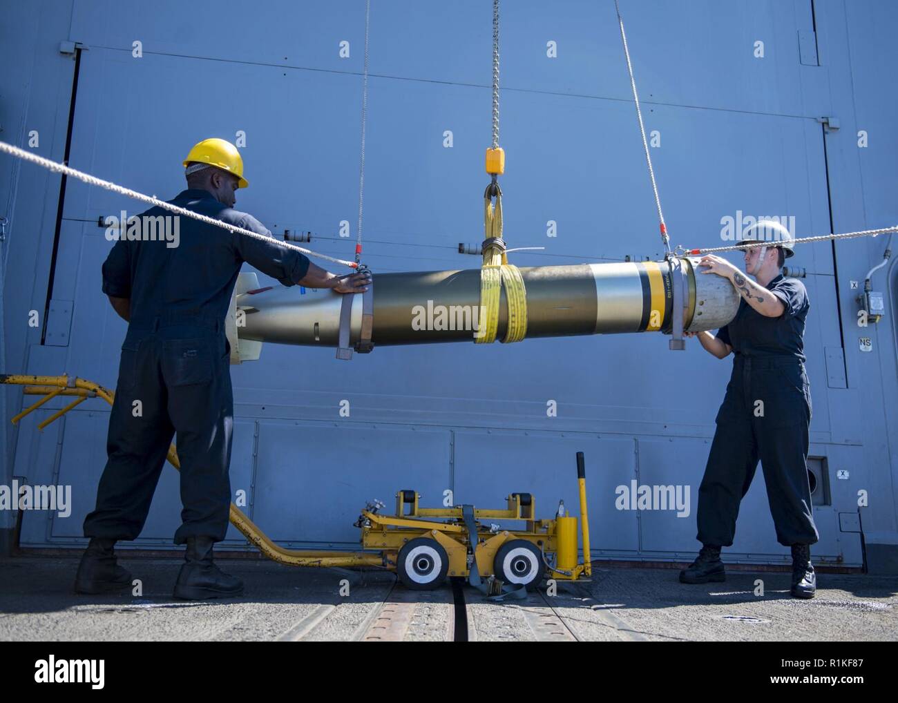 PACIFIC OCEAN (Oct. 14, 2018) Sonar Technician 1st Class Larry Lowe, left, from Los Angeles, and Sonar Technician Seaman Kimber Christie guide a MK46 torpedo as it is relocated from the surface-vessel torpedo tubes to the torpedo magazine aboard the Arleigh-Burke class guided-missile destroyer USS Michael Murphy (DDG 112). Michael Murphy is underway conducting routine operations in the 3rd Fleet area of operations. Stock Photo