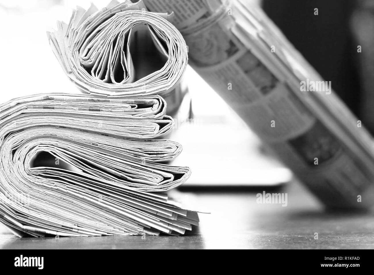 Newspapers and computer. Folded and rolled papers and magazines on table in front of open laptop. Concept for news, different sources of information Stock Photo
