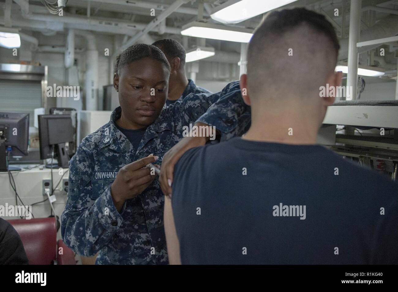 SAN DIEGO (Oct. 16, 2018) Hospital Corpsman 3rd Class Mercy Onwunta, from Bronx, N.Y., administers an influenza virus vaccine to Aviation Electronics Technician Airman Nicholas Myers, from Greenville, Ohio, in the medical ward aboard the amphibious assault ship USS Bonhomme Richard (LHD 6). Bonhomme Richard is in its homeport of San Diego. Stock Photo
