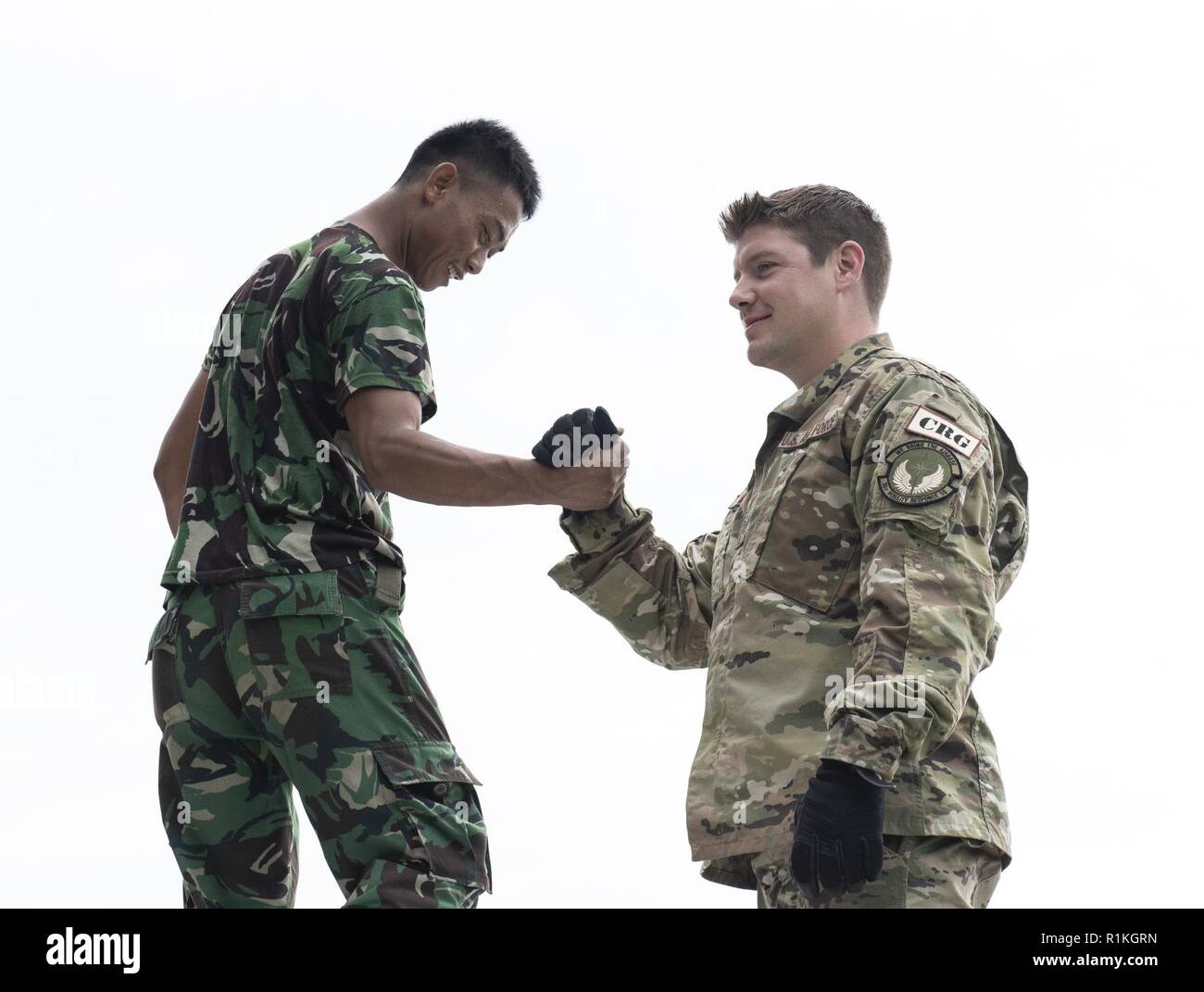 U.S. Air Force Tech. Sgt. Chad Davis, 36th Mobility Response Squadron command and control operator, at Andersen Air Force Base, Guam shakes hand with an Indonesian military member after assembling a U.S. Agency for International Development (USAID) pallet in Balikpapan, Indonesia Oct. 12, 2018. USAID is airlifting    over 2,210 rolls of heavy-duty plastic sheeting to provide emergency shelter for 110,500 people in Indonesia and is working with its partners to provide emergency shelter kits, blankets, hygiene kits, solar-powered lamps, other critical relief supplies. USAID has also made it a pr Stock Photo