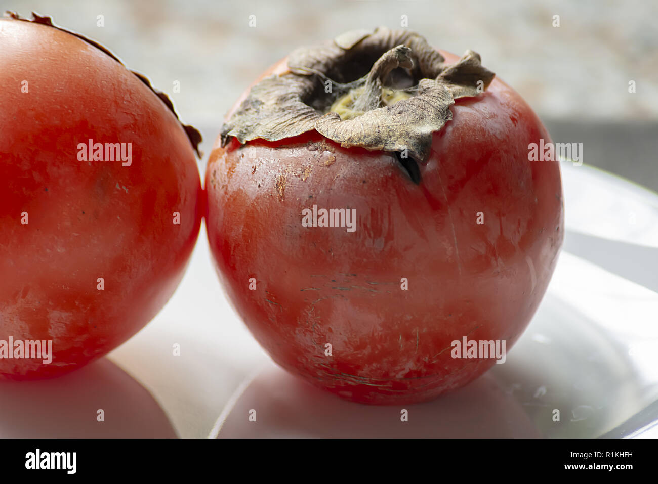 two khaki fruits in the plate close-up Stock Photo