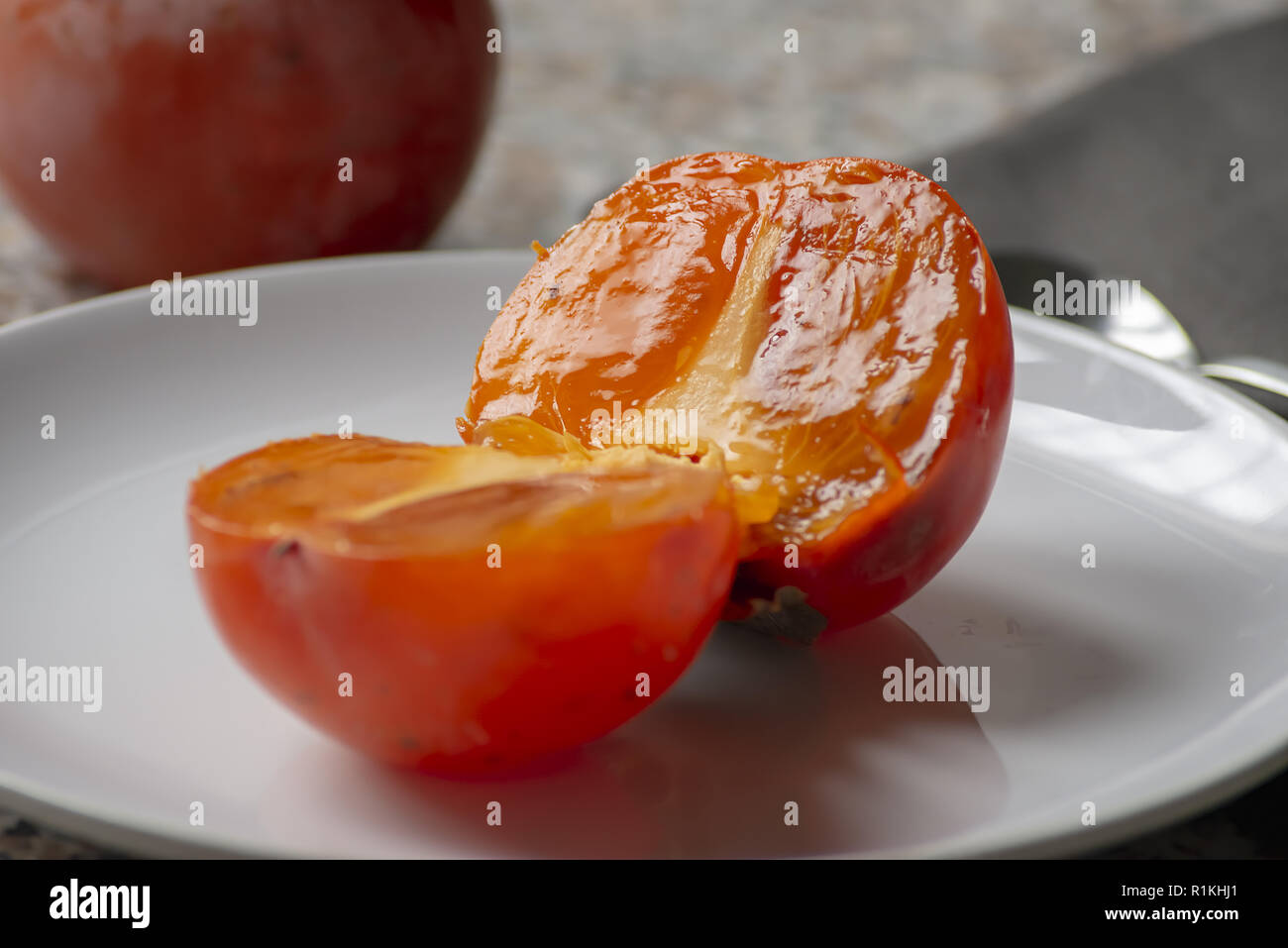 fruit of khaki in the plate cut in half close-up Stock Photo