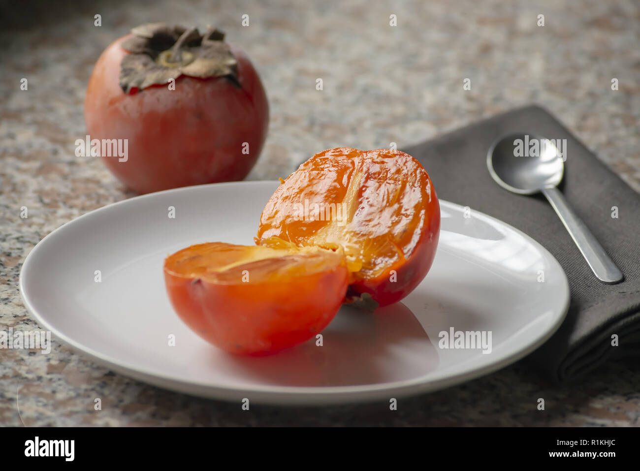kaki fruit in the plate cut in half by close Stock Photo
