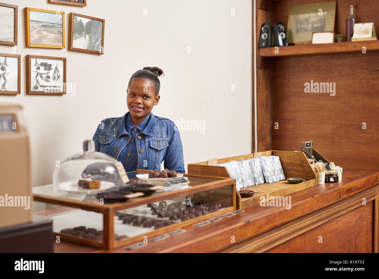 Artisanal chocolate shop owner smiling while standing behind her counter Stock Photo