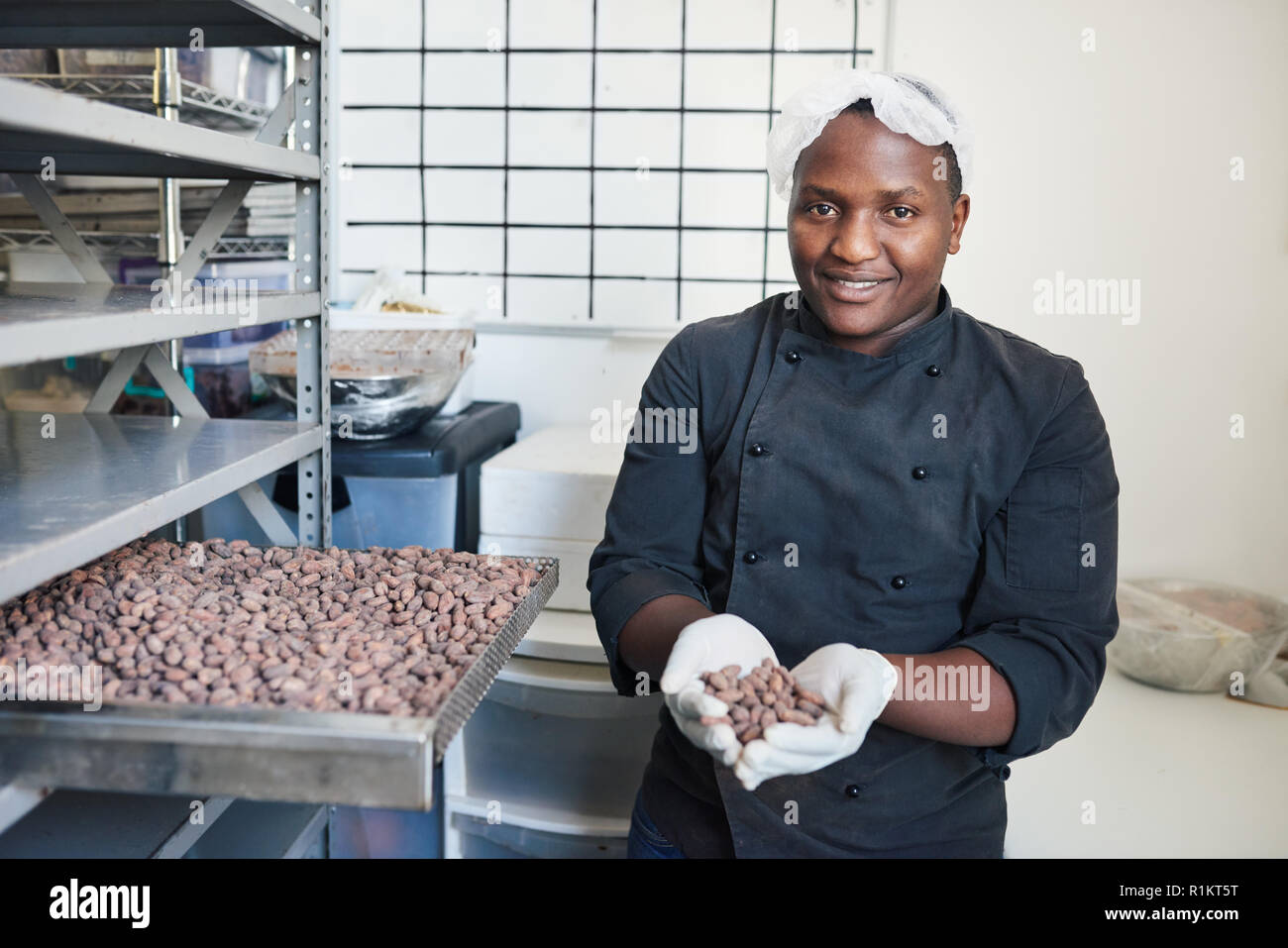 Smiling worker selecting cocoa beans from a factory tray Stock Photo
