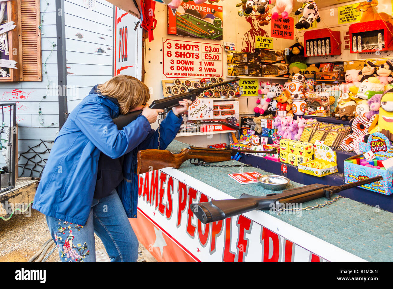Teenager firing an air rifle at a fairground shooting gallery, London, UK Stock Photo