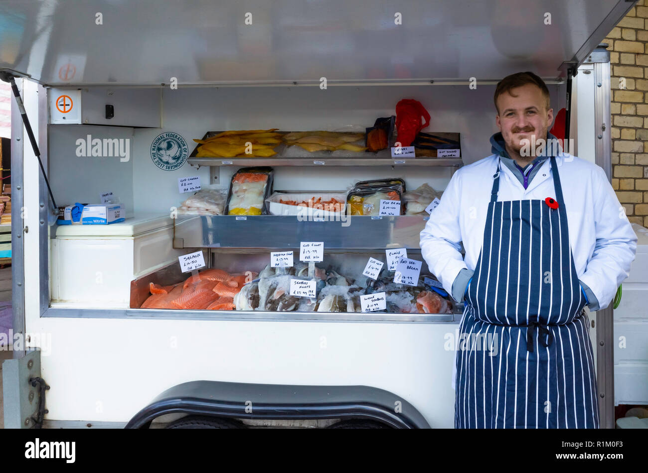 Fishmonger gentleman stallholder with display of his fresh fish for sale in Saltburn Farmers Market in Autumn with 2018 price tags Stock Photo