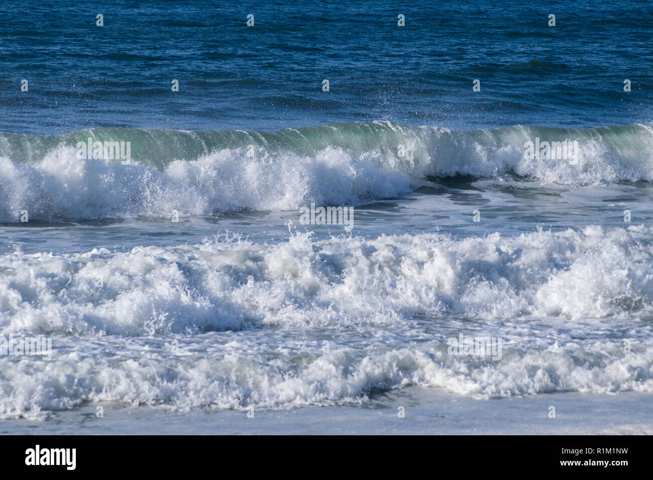 sea waves breaking on the shore of the beach splashing and forming foam ...