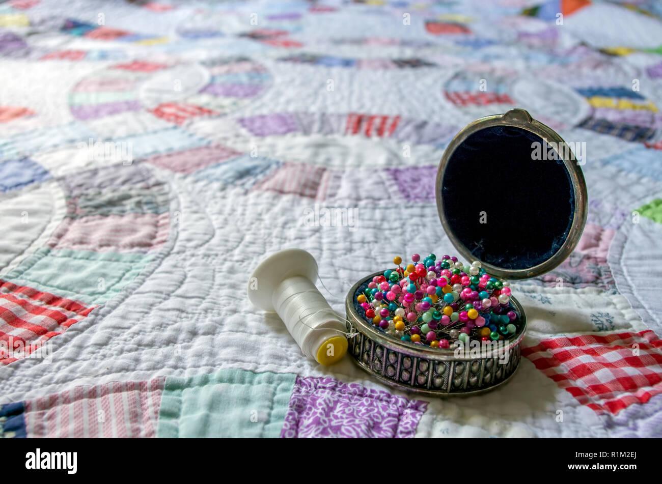 White and colorful patchwork hand sewn double wedding ring quilt with thread and pins from the American South Stock Photo