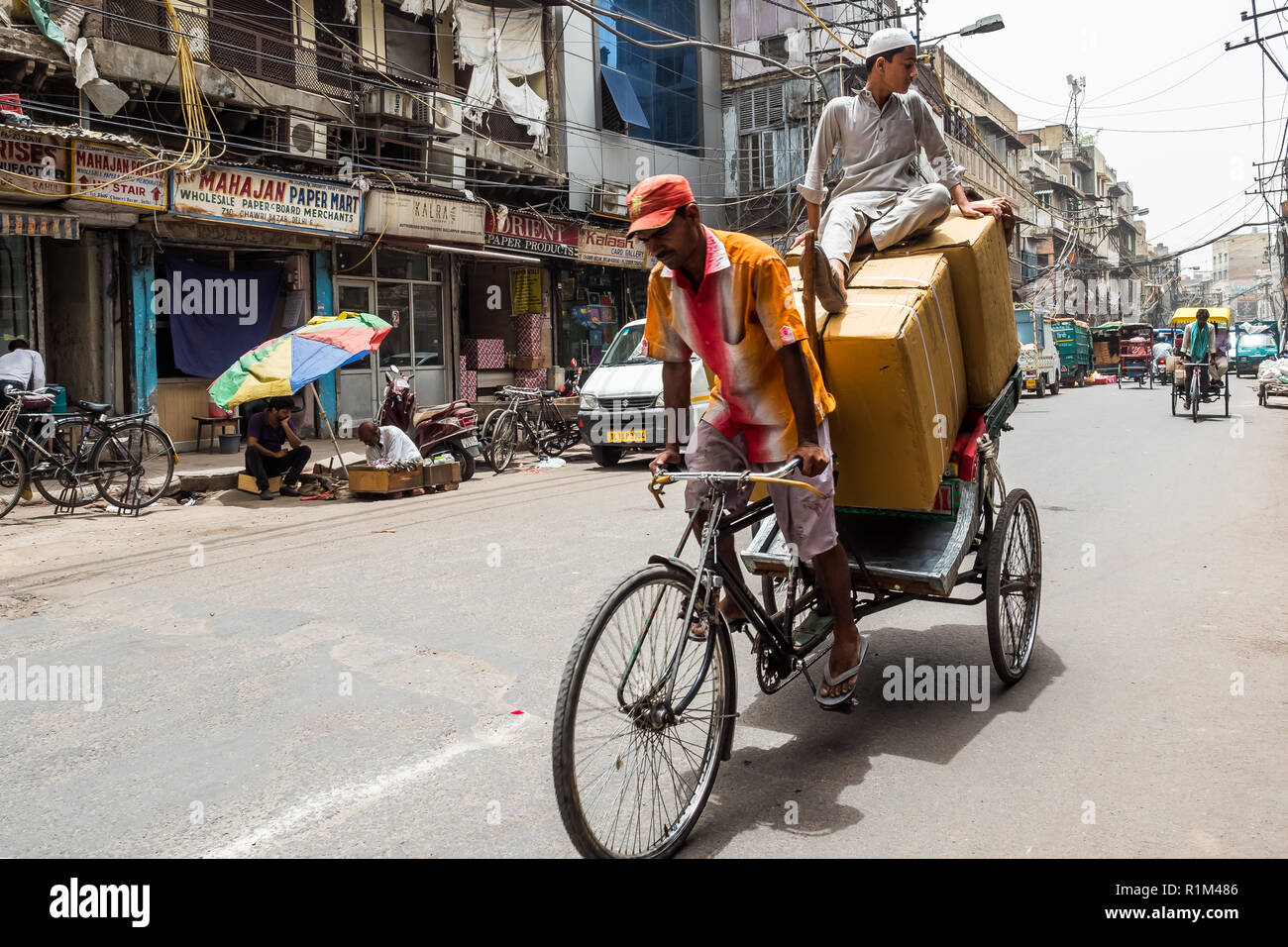 TMan carrying luggage and passenger by rickshaw. Old Delhi. India 2018 Stock Photo