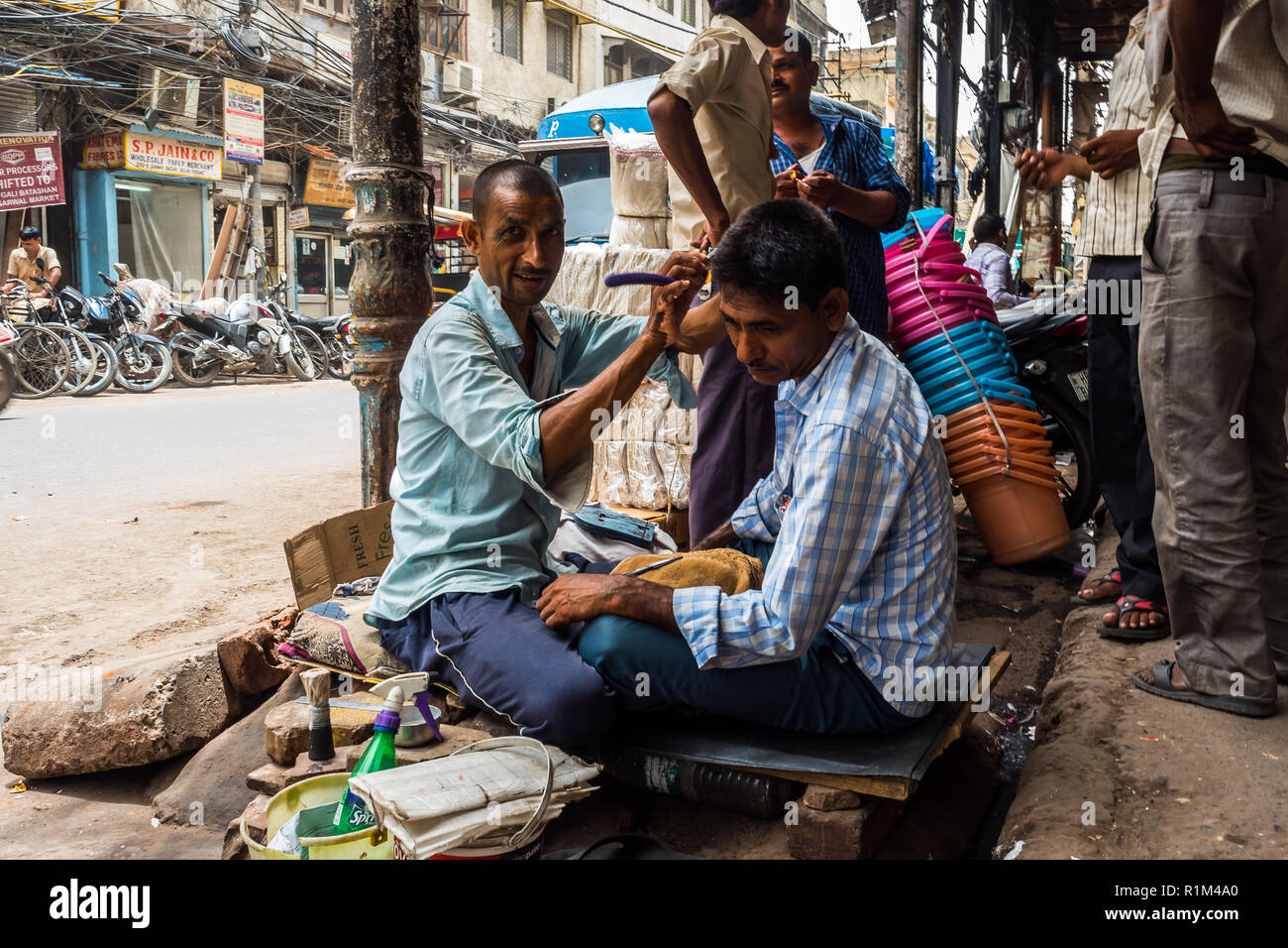 cityscape,Street hairdresser is cutting a man in Delhi. June 2018 Stock Photo