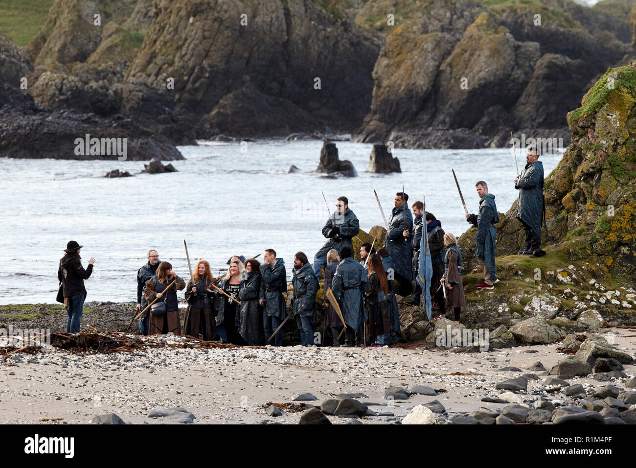Tourists wearing costumes holding swords on a Game of Thrones guided coach tour in Ballintoy on Northern Irelands north coast Stock Photo