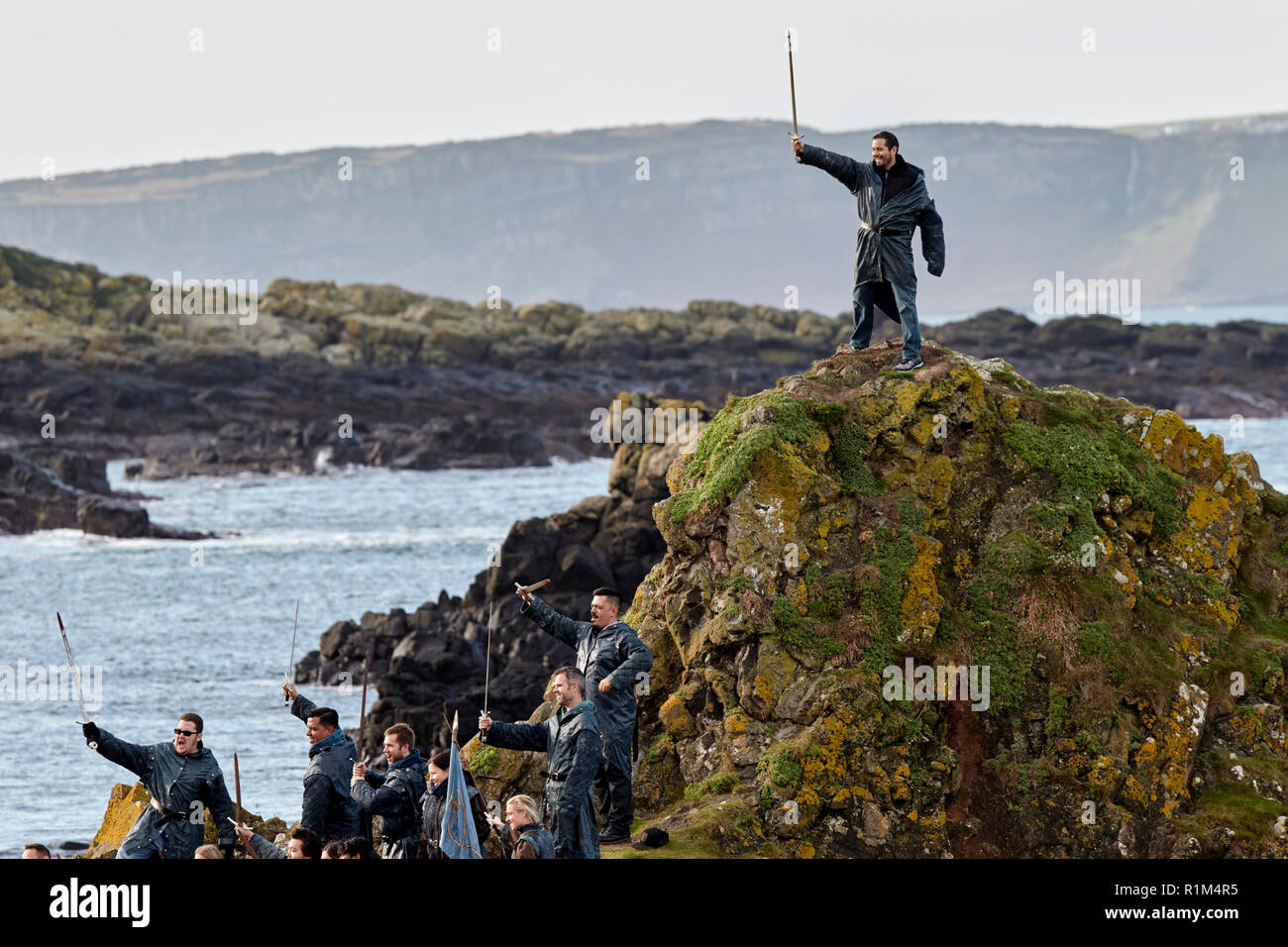 Tourists wearing costumes holding swords on a Game of Thrones guided coach tour in Ballintoy on Northern Irelands north coast Stock Photo