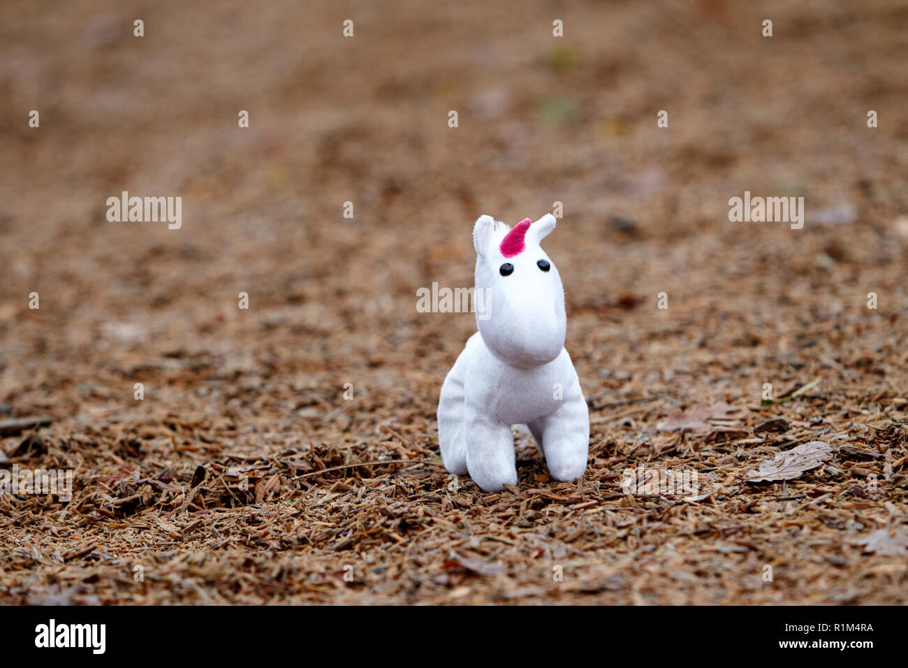Little girl childs soft toy unicorn lost in a childrens playground Stock Photo