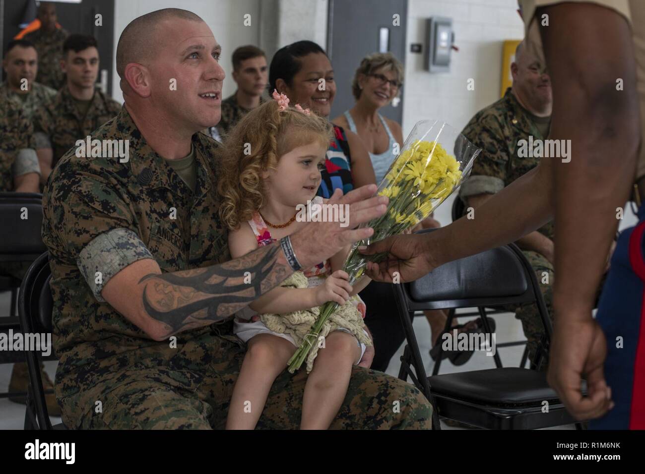 U.S. Marine Corps Sgt. Maj. Phillip Anderson, the newly appointed squadron sergeant major of Marine Medium Tiltrotor Squadron (VMM) 363,  and his daughter are presented flowers during an appointment ceremony, Oct. 19, 2018. VMM-363, nicknamed the Lucky Red Lions, arrived to Hawaii earlier this year increasing the combat capability and crisis response within the Indo-Pacific region. Stock Photo