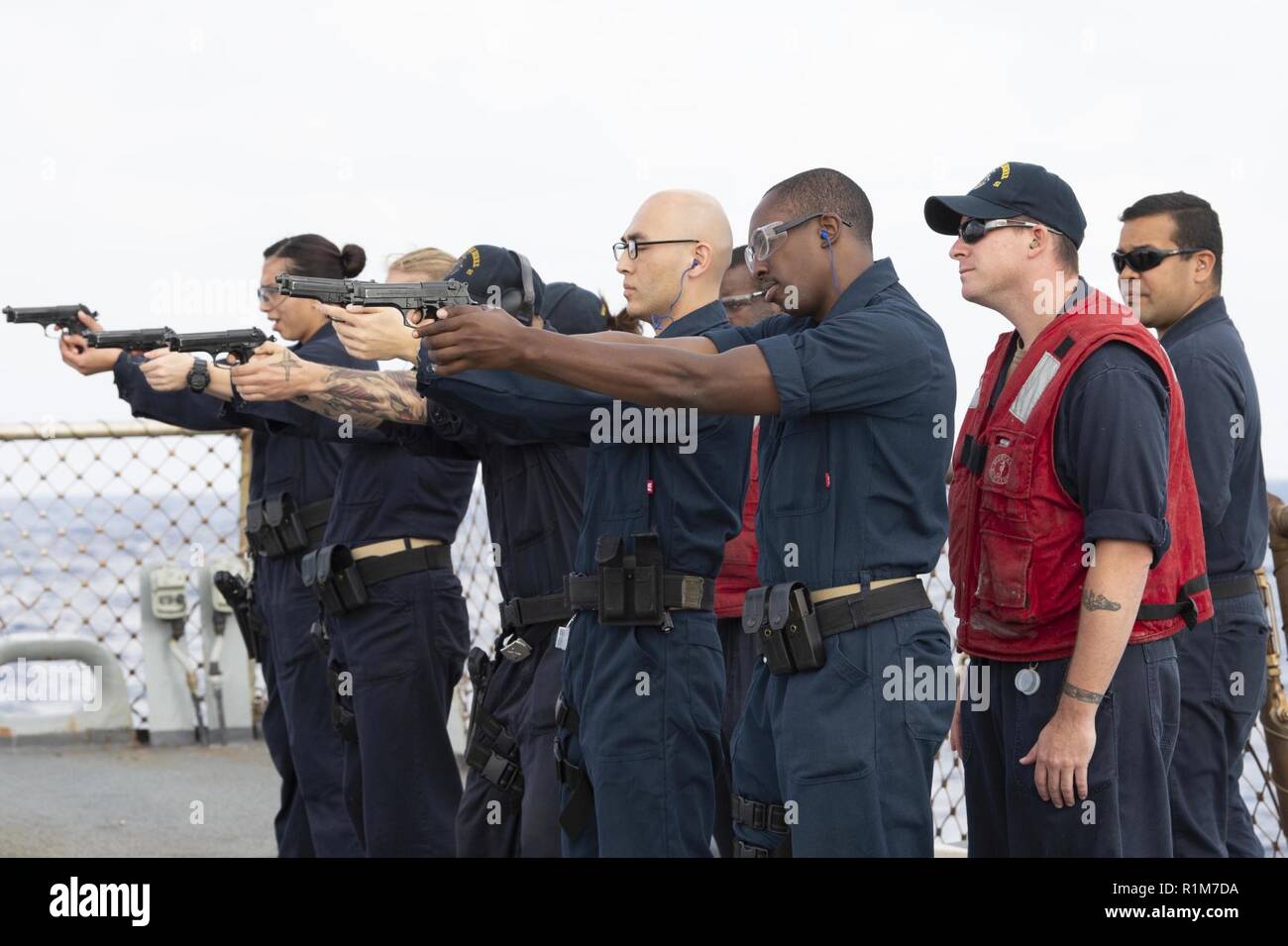 MEDITERRANEAN SEA (Oct. 17, 2018) Sailors fire M9 service pistols during a small-arms qualification course aboard the Arleigh Burke-class guided-missile destroyer USS Arleigh Burke (DDG 51) in the Mediterranean Sea Oct. 17, 2018. Arleigh Burke, homeported at Naval Station Norfolk, is conducting naval operations in the U.S. 6th Fleet area of operations in support of U.S. national security interests in Europe and Africa. Stock Photo