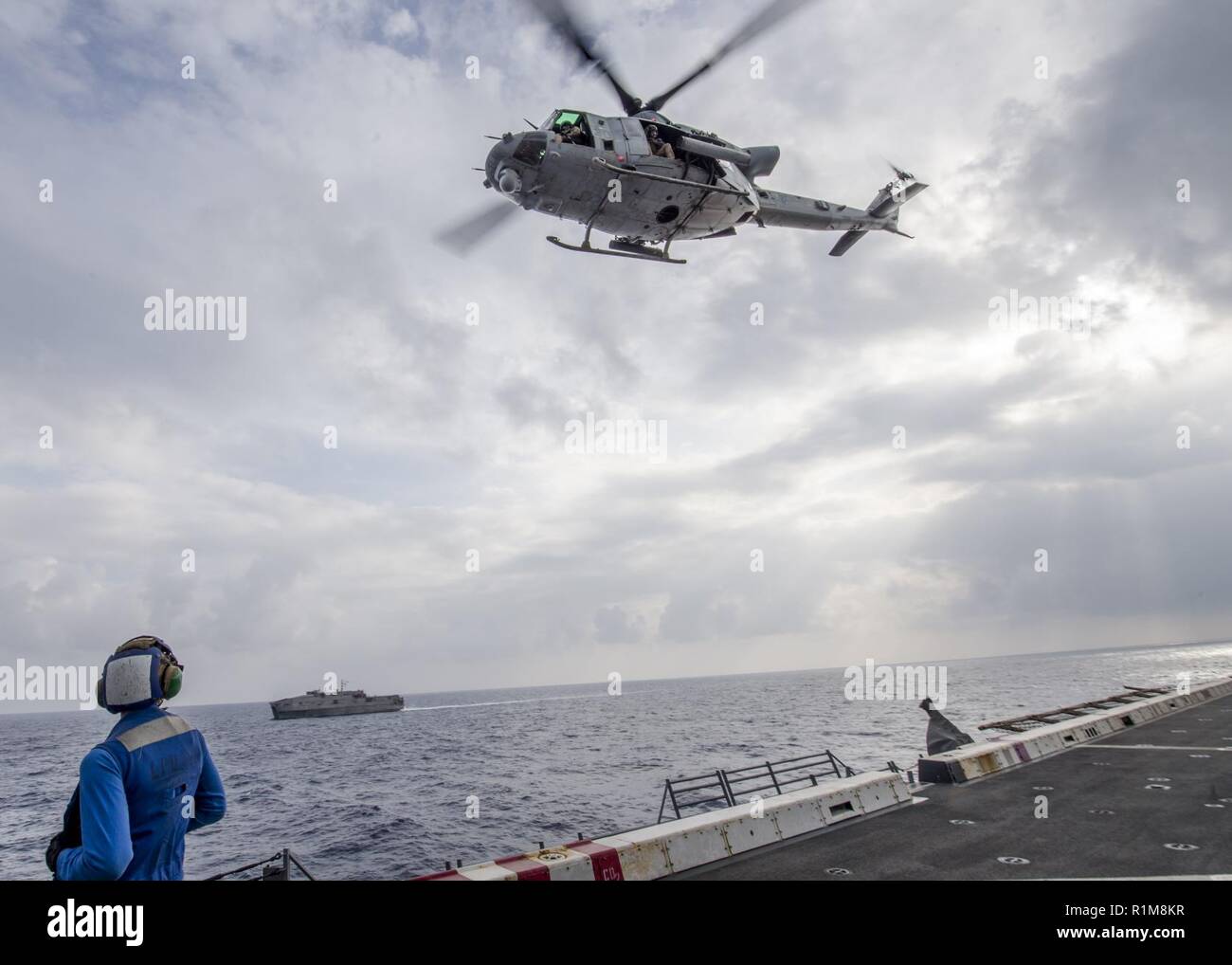 MEDITERRANEAN SEA (Oct. 20, 2018) Damage Controlman 3rd Class Wayne L. Batten, watches a UH-1Y Venom helicopter, attached to Marine Medium Tiltrotor Squadron (VMM) 166 (Reinforced), take off from the flight deck of the San Antonio-class amphibious transport dock ship USS Anchorage (LPD 23) during flight operations with the Spearhead-class expeditionary fast transport ship USNS Carson City (T-EPF-7) in the Mediterranean Sea, Oct. 20, 2018. Anchorage and embarked 13th Marine Expeditionary Unit are deployed to the U.S. 6th Fleet area of operations as a crisis response force in support of regional Stock Photo