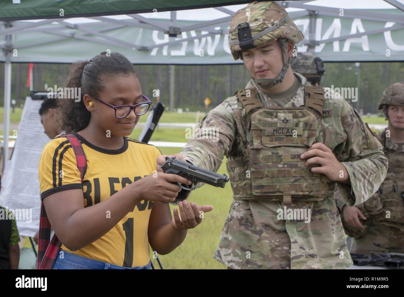 Pfc. Justin Mclain of 2nd Battalion, 69th Armored Regiment, 2nd Armored Brigade Combat Team, 3rd Infantry Division watches as a family member handles an unloaded M9 pistol. 2-69 AR hosted a “Family Day” during a gunnery range at Fort Stewart, Ga., Oct. 20.  The event allowed families to see tanks firing and handle weaponry in a safe, controlled setting. Stock Photo