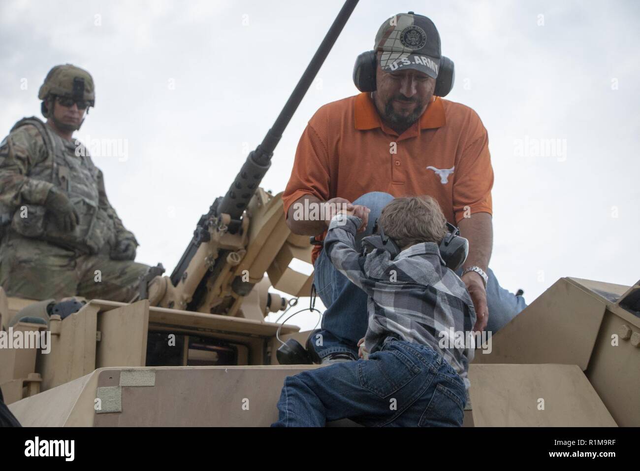 Mario Rosas helps his son onto a M1A1-SA Abrams tank. 2nd Battalion, 69th Armored Regiment, 2nd Armored Brigade Combat Team, 3rd Infantry Division hosted a “Family Day” during gunnery at Fort Stewart, Ga., Oct. 20. The event allowed families to see tanks firing and handle weaponry in a safe, controlled setting. Stock Photo