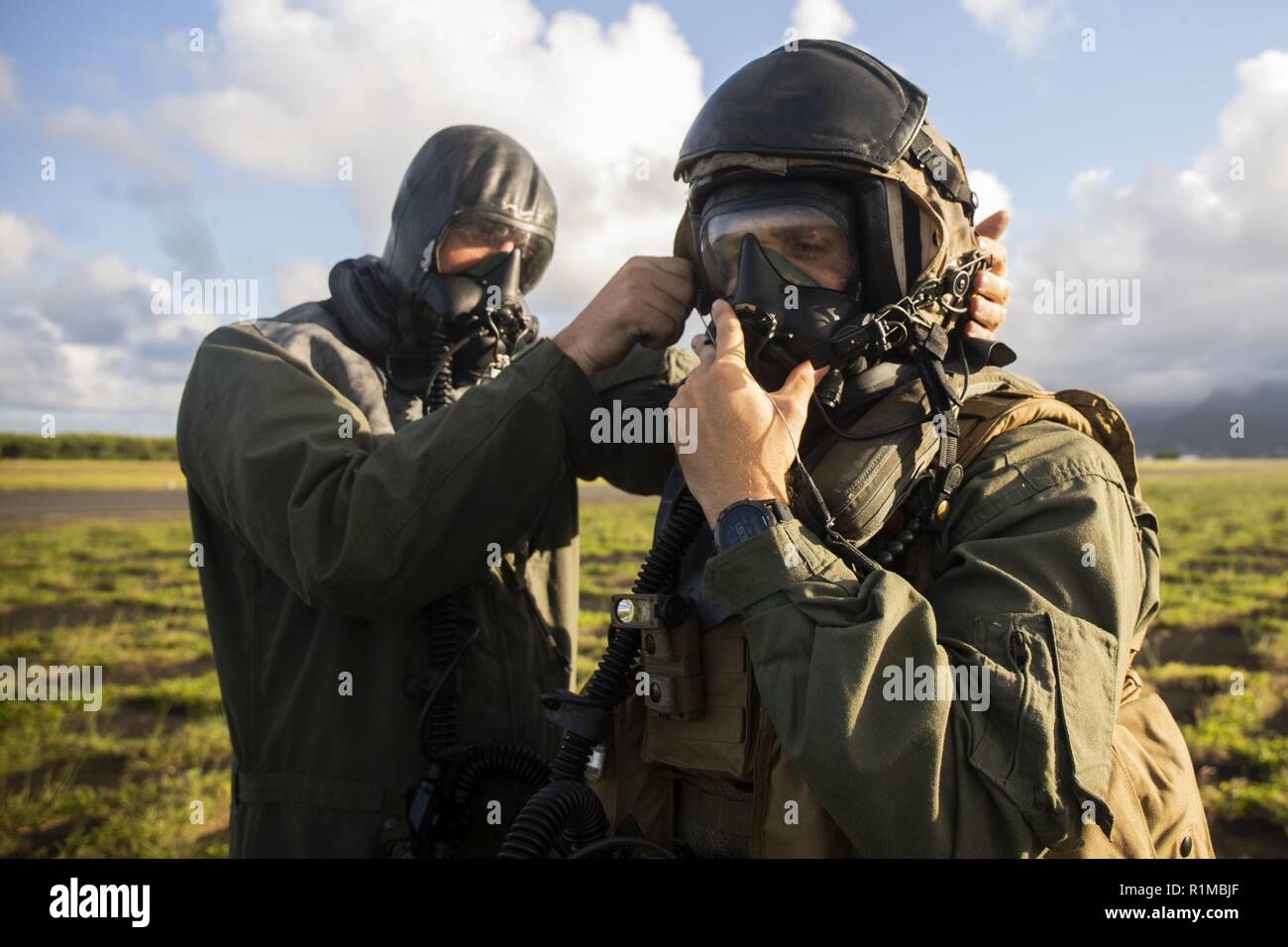 U.S. Marine Corps Maj. Ryan Pallas (right), a CH-53E Super Stallion aircraft commander and Gunnery Sgt. Todd Bauer, a crew chief, with Marine Heavy Helicopter Squadron 463, Marine Aircraft Group 24, dawn their gas masks during Chemical, Biological, Radioactive and Nuclear Environment (CBRNE) helicopter training, Marine Corps Air Station Kaneohe Bay, Oct. 22, 2018. The flight was conducted to produce readiness within the squadron. Stock Photo