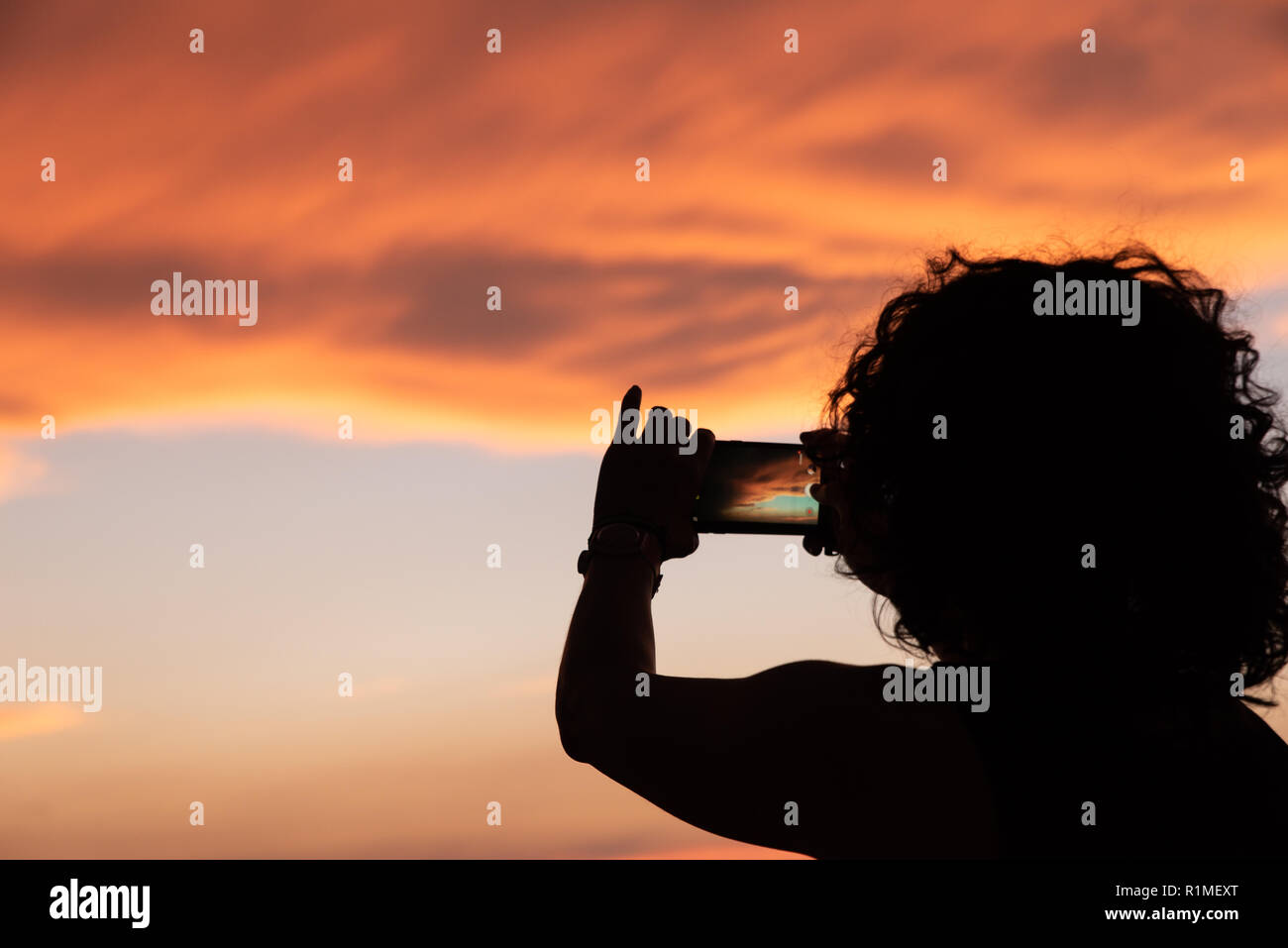 woman taking sunset photos with her mobile Stock Photo