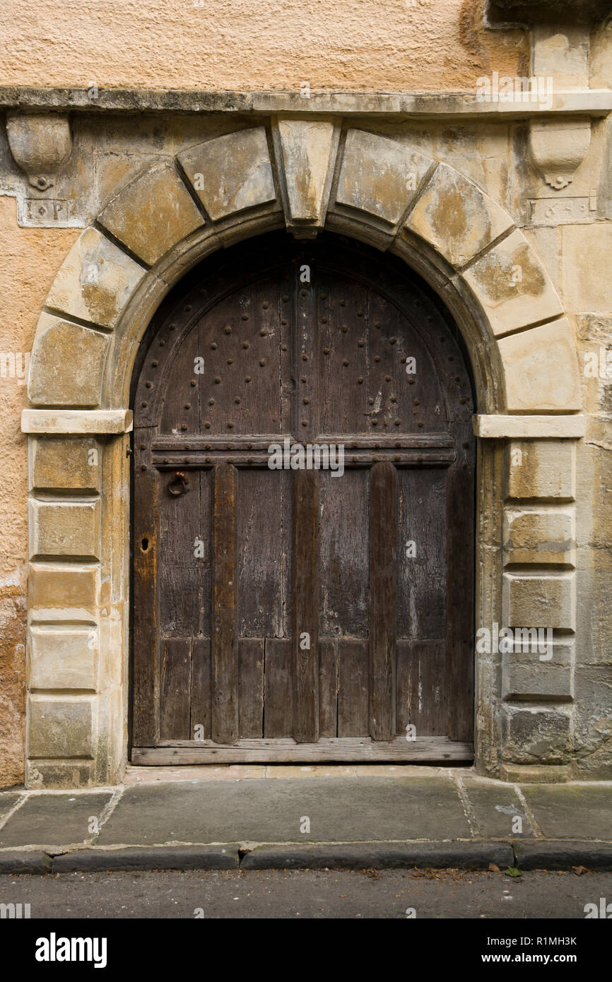 An ancient studded wood entrance door on a street in Cirencester, Gloucestershire, UK Stock Photo